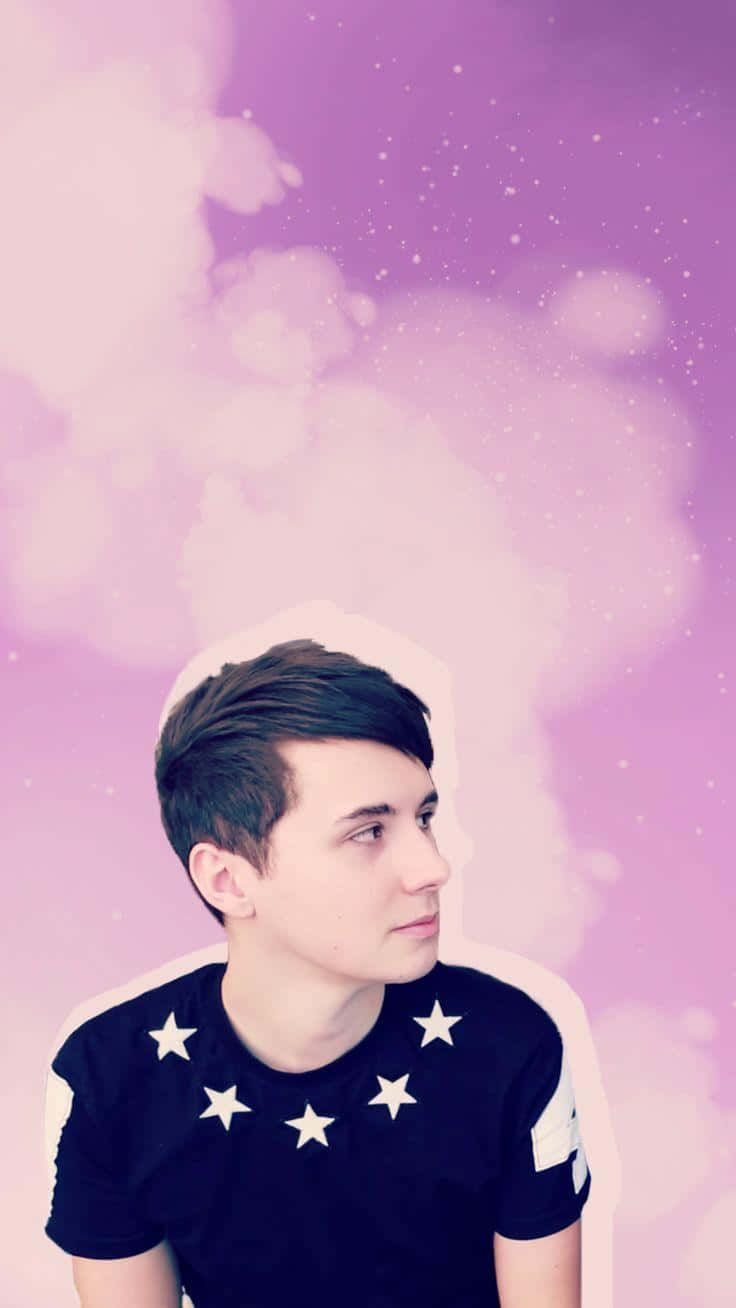dan and phil 桌布 壁紙 — 一位身穿星星圖案襯衫的年輕男子，若有所思地凝視著夢幻般的紫色天空，天空中有柔軟的雲朵和閃爍的粒子。