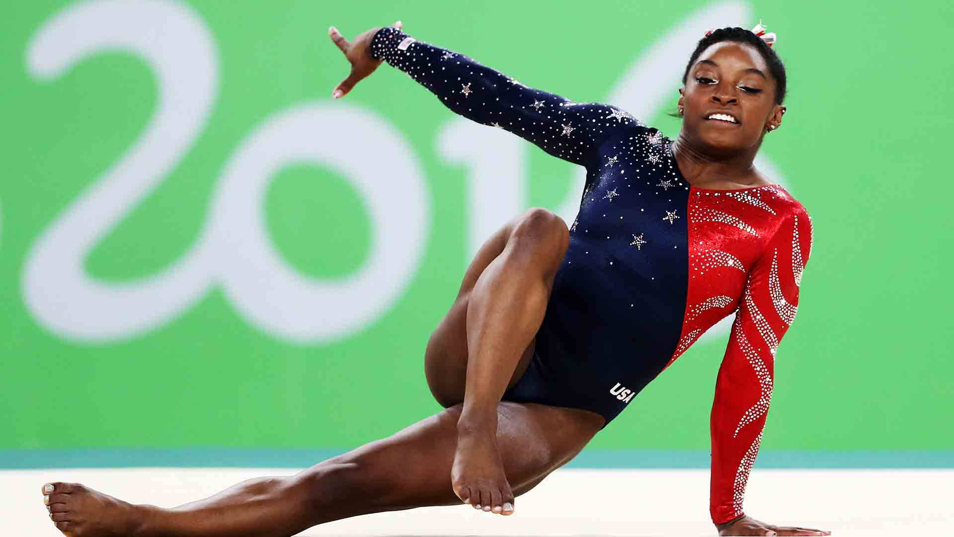 Simone Biles 桌布 壁紙 — 一位身穿星條旗緊身衣的女體操運動員在綠色背景前執行動態地板動作，背景中可見「2016」。