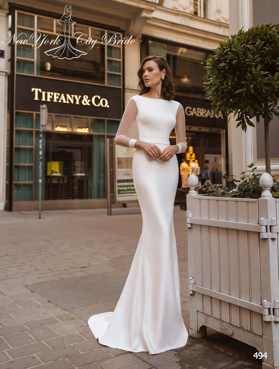 Bride's Dress 桌布 壁紙 — 一位身穿時尚白色美人魚婚紗的女性，優雅地站在城市人行道上，旁邊是Tiffany & Co.的店面。