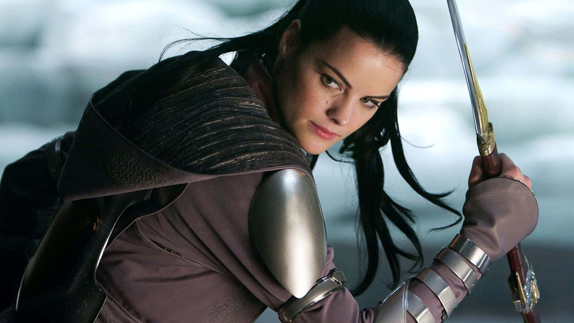 Lady Sif 桌布 壁紙 — 一位身穿暗色盔甲的女戰士在雪景背景下緊握劍柄，神情專注。
