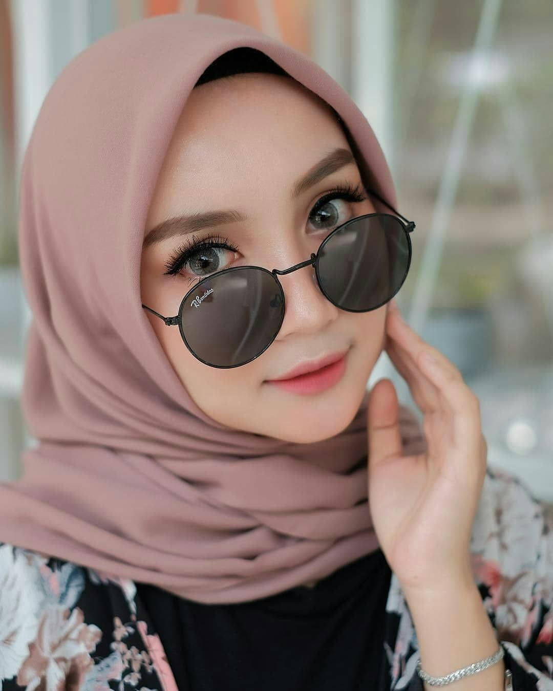 muslim 桌布 壁紙 — 一位身穿柔和粉紅色頭巾和圓形太陽眼鏡的女性，以平靜的表情輕輕觸摸臉龐。