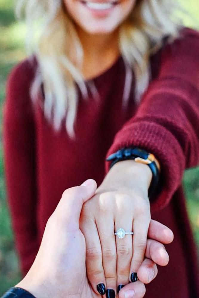 engagement 桌布 壁紙 — 一位身穿栗色毛衣的快樂女士伸出手，展示一枚閃閃發光的鑽石訂婚戒指。