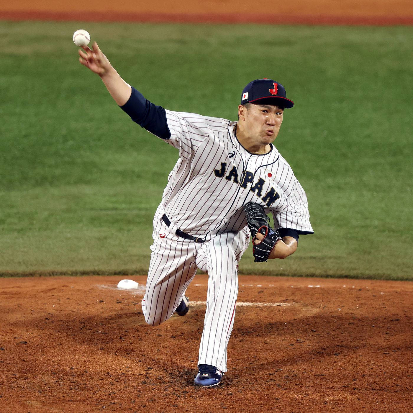 masahiro tanaka 桌布 壁紙 — 一位身穿條紋球衣的日本棒球投手在夜間燈光明亮的球場上投球。