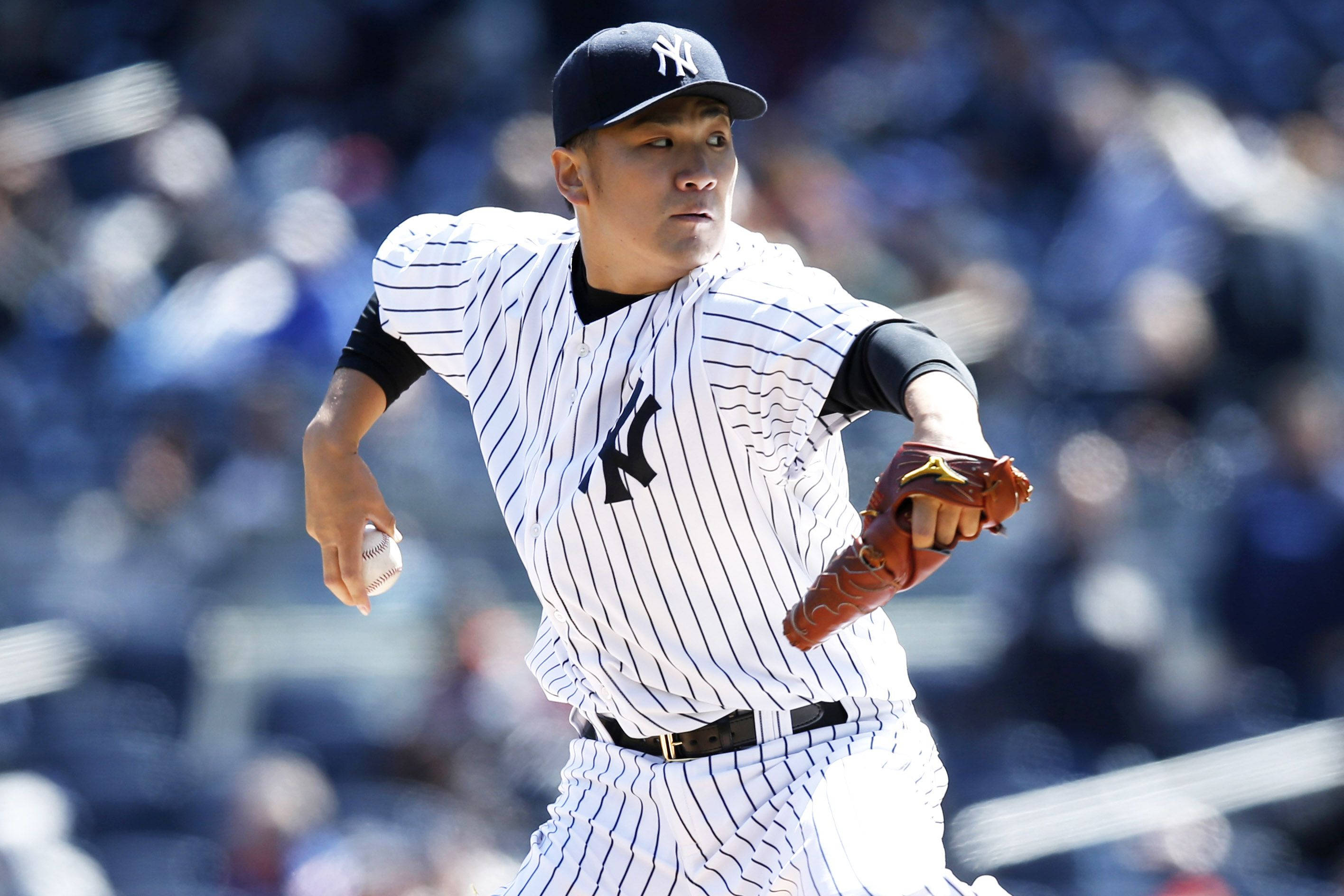 masahiro tanaka 桌布 壁紙 — 一位身穿條紋球衣的棒球投手在明亮的球場燈光下準備投球。