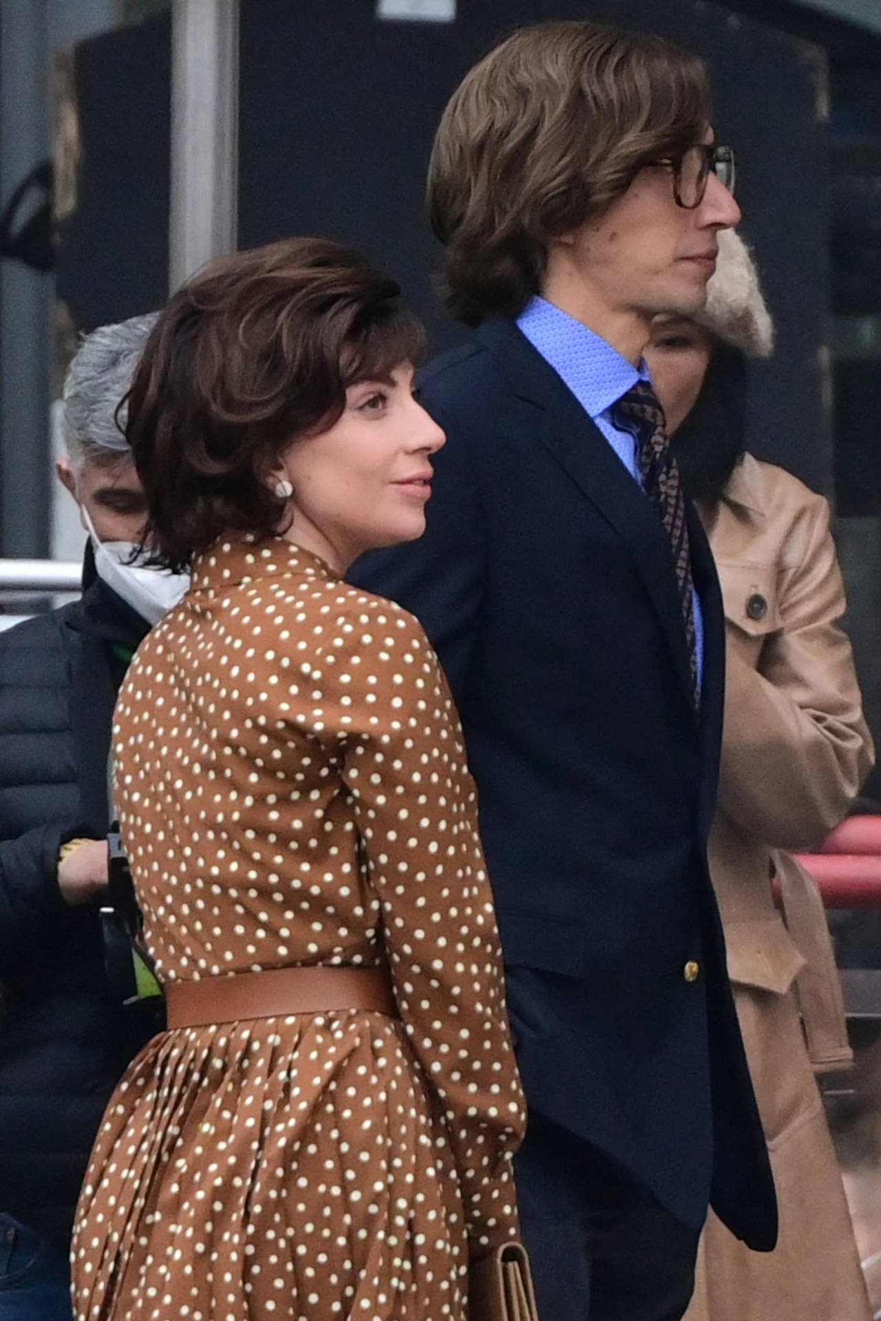 身穿圓點裙的女子與穿西裝的男子在街上同行。 — Gucci 之家 壁紙