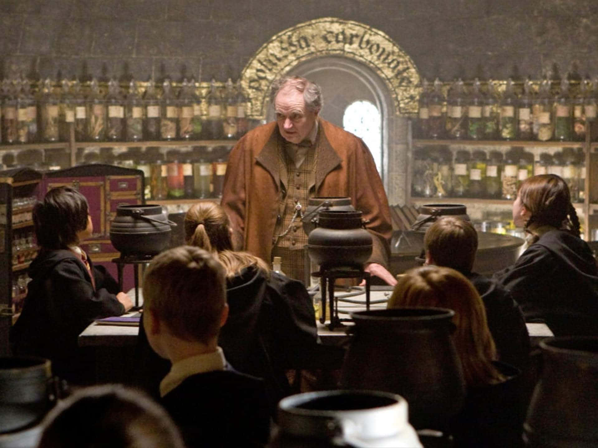 The Hogwarts Potions Class 桌布 壁紙 — 一位身穿棕色長袍的嚴厲巫師在一個充滿冒泡大鍋和魔法材料架的魔藥教室裡教導學生。