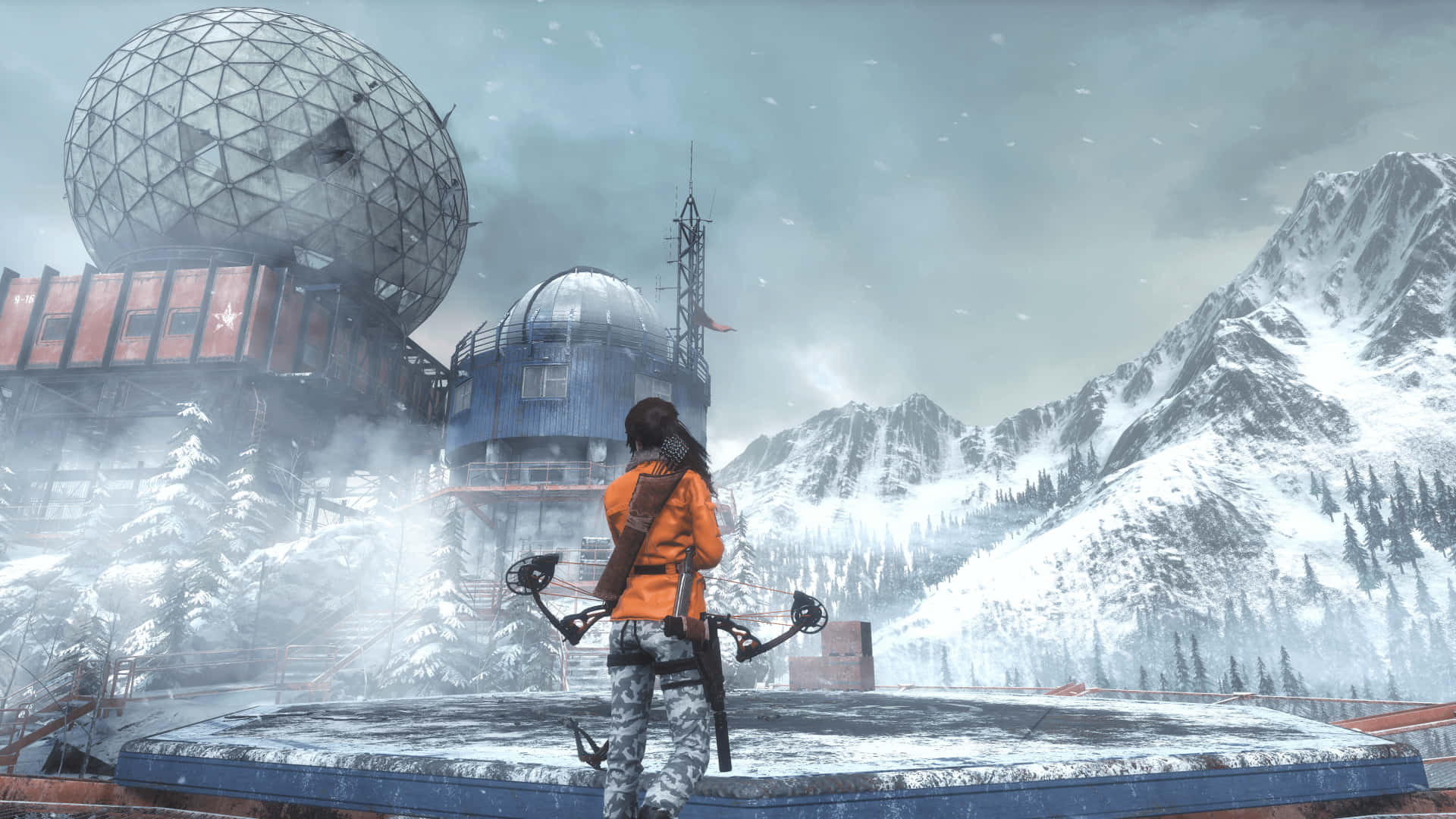 Lara Croft 桌布 壁紙 — 一位身穿橙色外套的孤獨冒險家站在白雪覆蓋的平台上，俯瞰著灰色天空下、坐落在雪山中的未來主義圓頂建築群。