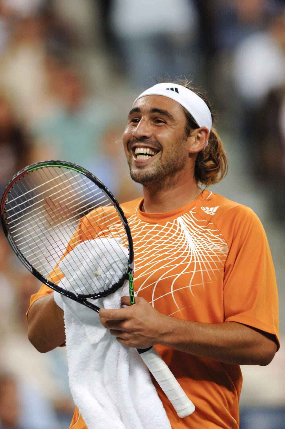 Tennis 桌布 壁紙 — 一位身穿橙色襯衫的快樂網球運動員在比賽中拿著球拍和毛巾大笑。