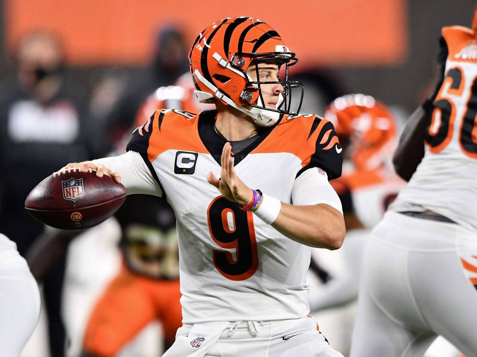 Joe Burrow 桌布 壁紙 — 一位身穿橙黑色球衣的辛辛那提猛虎四分衛在夜間比賽中準備擲出橄欖球。