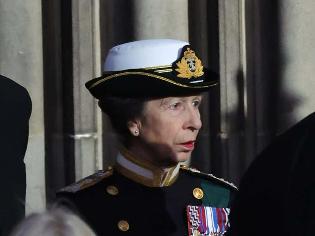 England 桌布 壁紙 — 一位身穿正式海軍制服、戴白帽和勳章的女性莊嚴地站在石柱前。