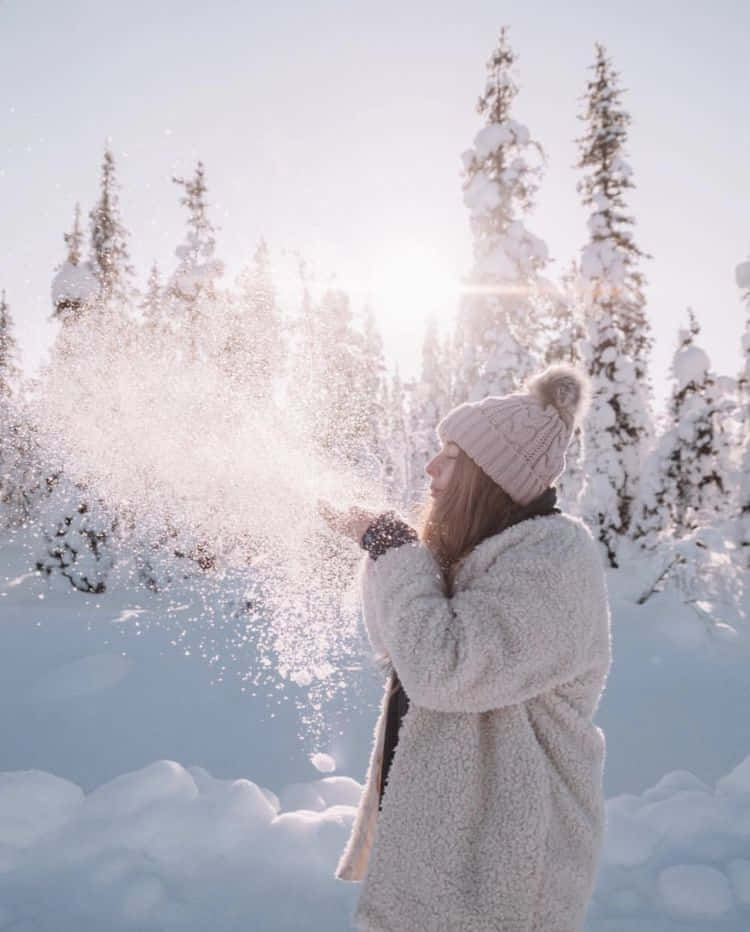 Winter Photography 桌布 壁紙 — 一位身穿毛絨白色外套和粉紅色毛帽的女性，在明亮的陽光冬日森林中拋雪。