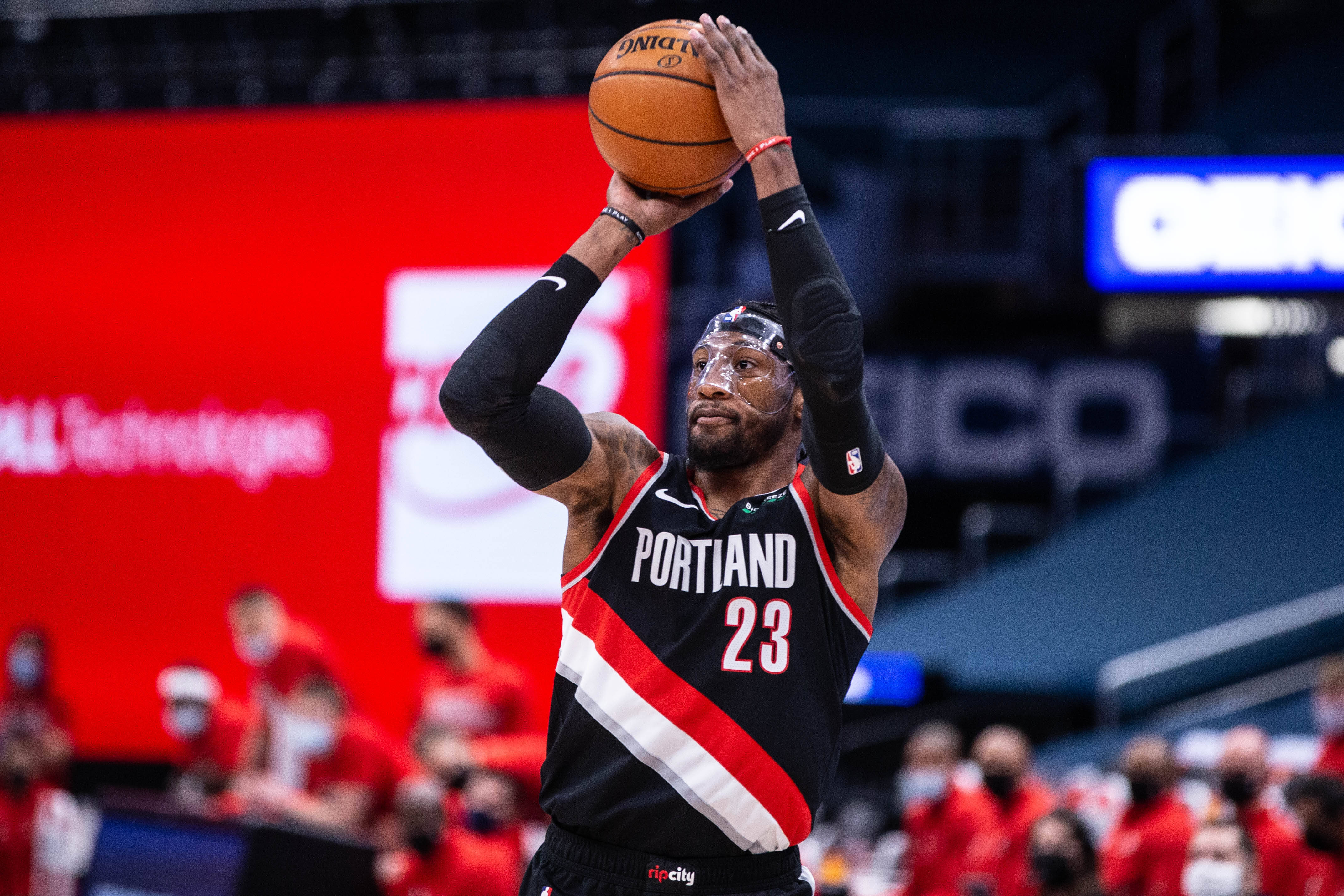 robert covington 桌布 壁紙 — 一位身穿波特蘭球衣的籃球運動員在場館燈光下投籃，身後紅色座位上的球迷模糊不清。