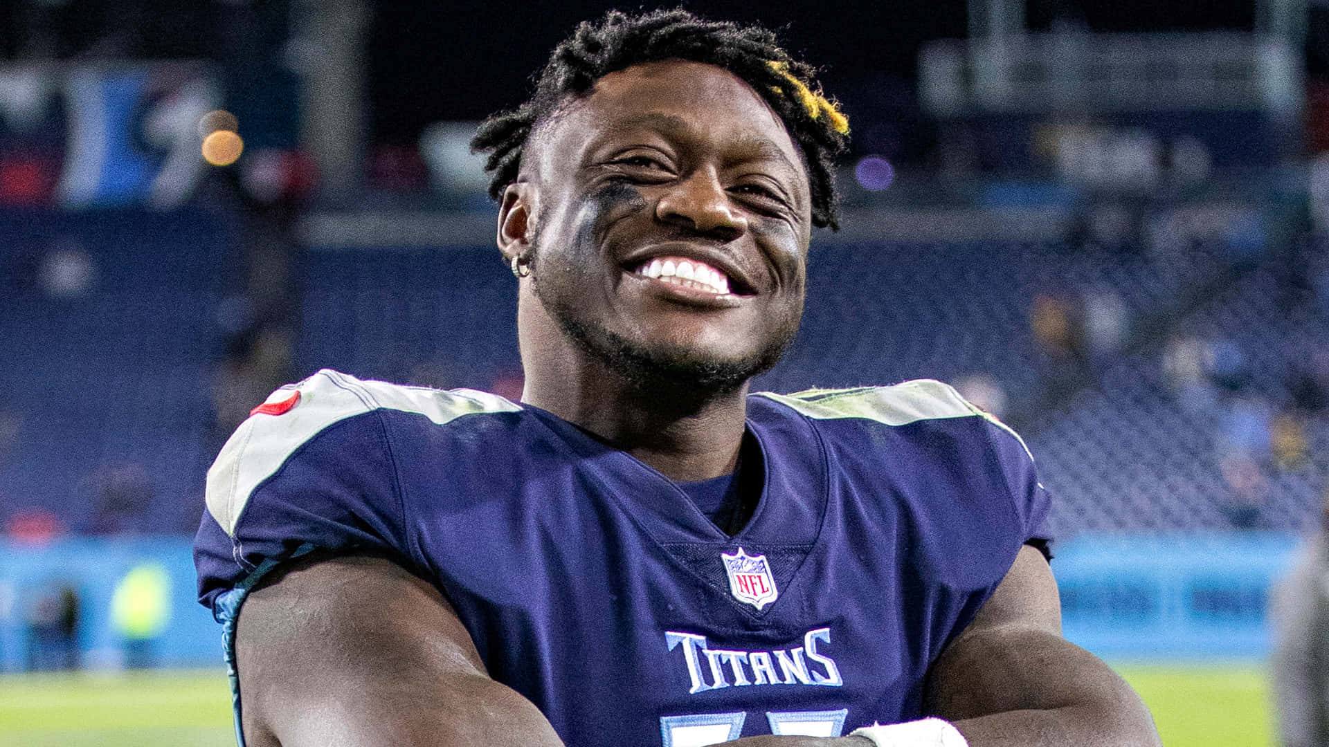 smiling 桌布 壁紙 — 一位身穿泰坦隊球衣的快樂NFL球員在夜間球場上露出燦爛的笑容。