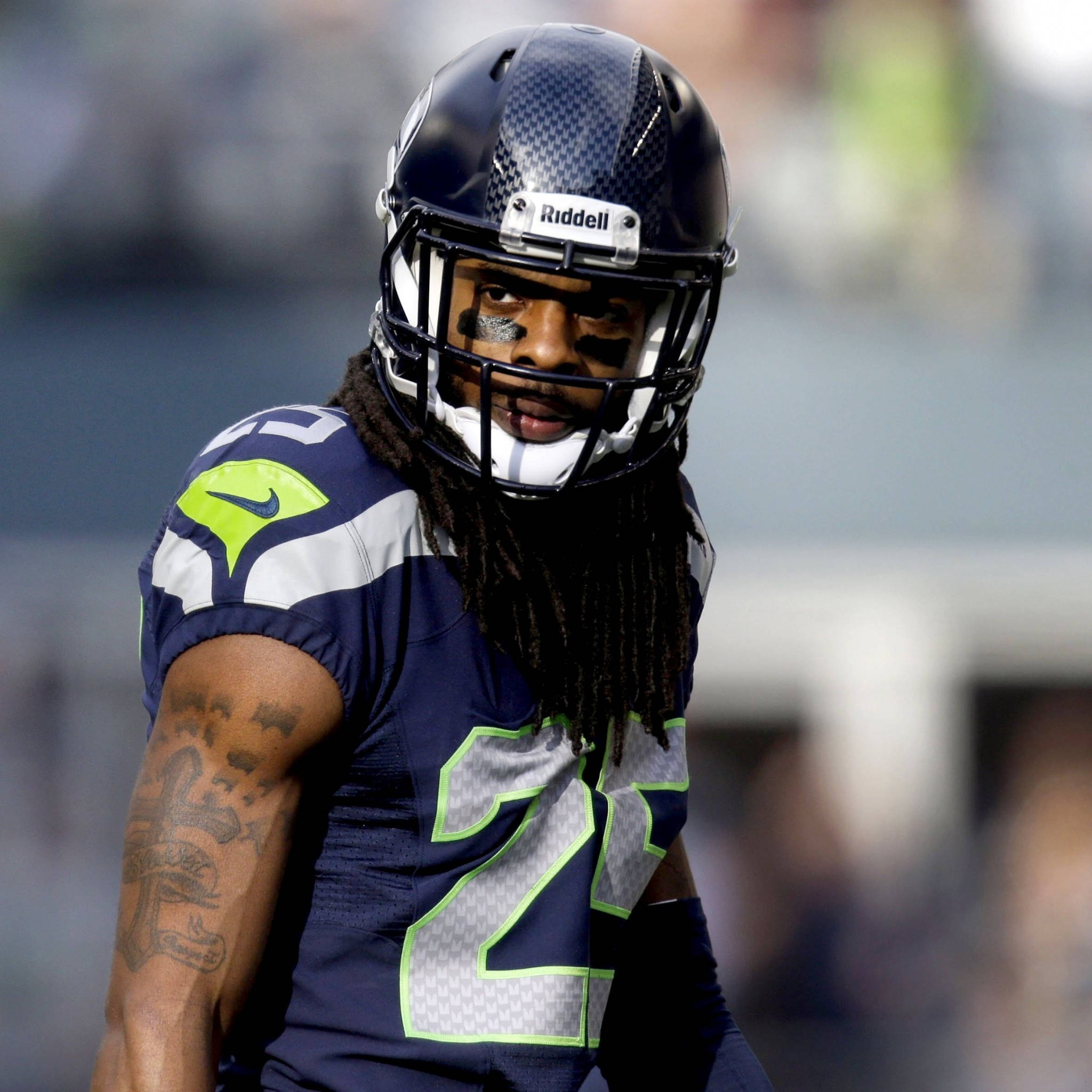 Seattle Seahawks 桌布 壁紙 — 一位身穿海軍藍和螢光綠色制服、背號22的西雅圖海鷹隊美式足球員在日間比賽中專注凝視。