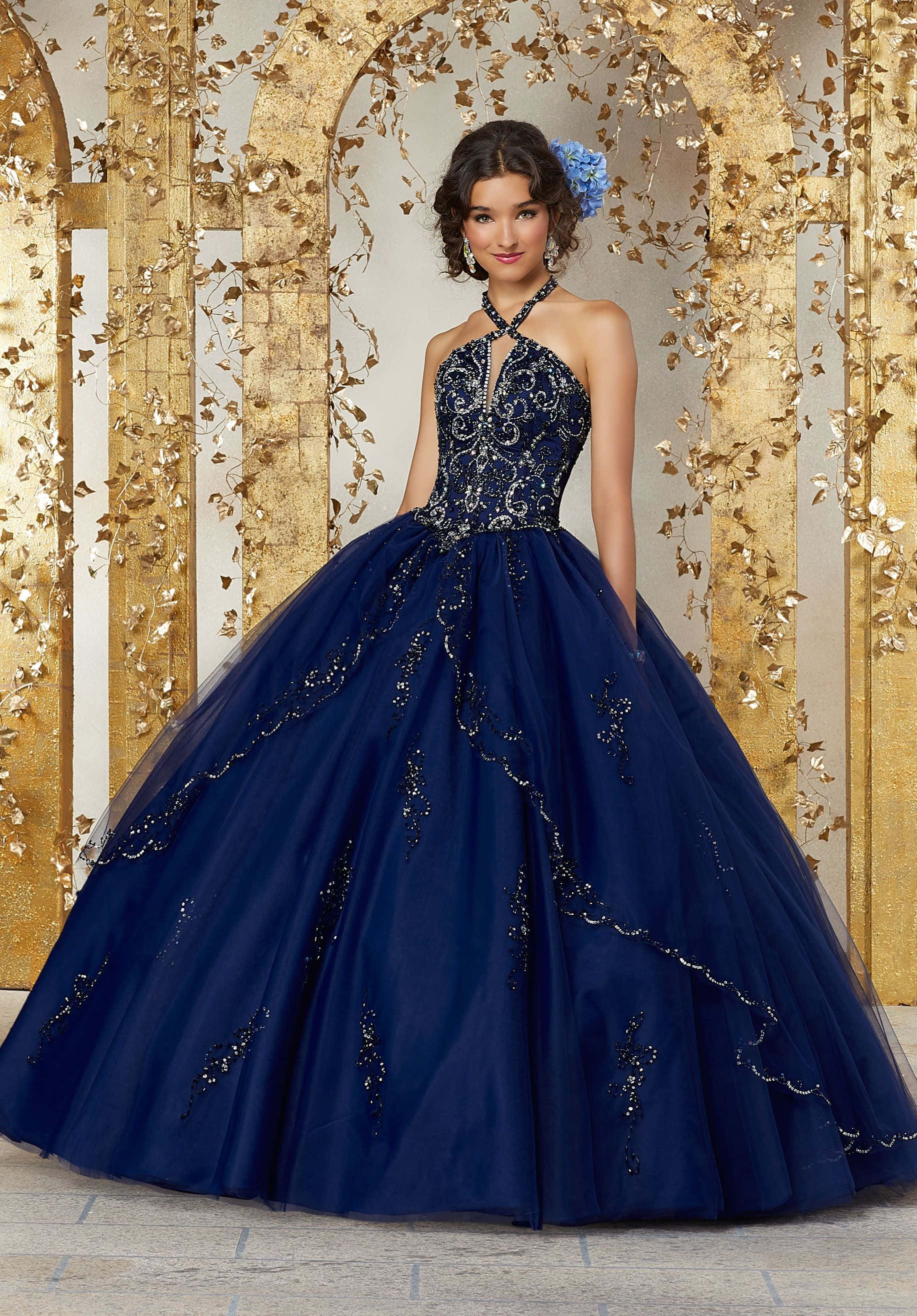 Navy Blue Dress 桌布 壁紙 — 一位身穿海軍藍珠飾舞會禮服的年輕女子，優雅地站在裝飾著葉狀藤蔓的金色拱門前。