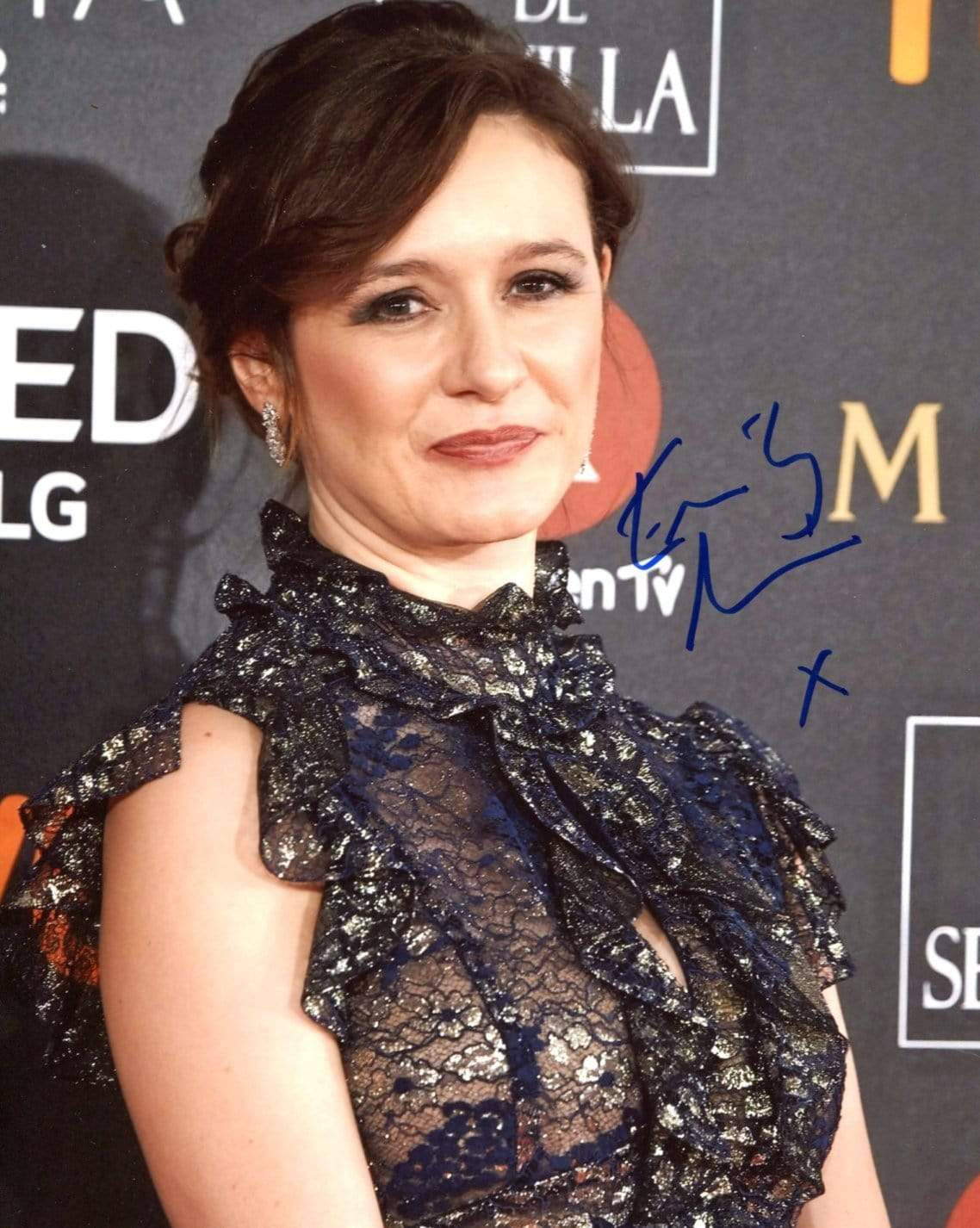 Celebrity 桌布 壁紙 — 一位身穿深色蕾絲裙的女性在背後有標誌的紅地毯活動中對著鏡頭微笑。