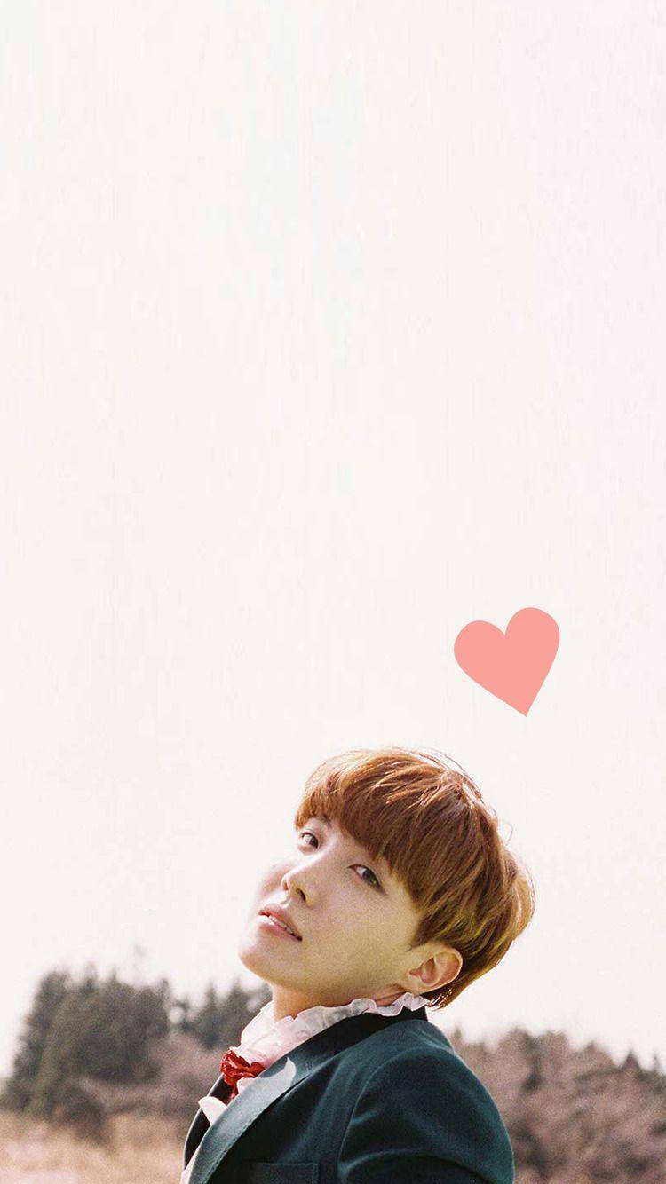 Cute Bts 桌布 壁紙 — 一位身穿深色西裝外套和紅色領結的年輕男子，在明亮的天空下抬頭微笑，一個粉紅色的心形漂浮在他的頭頂上方。