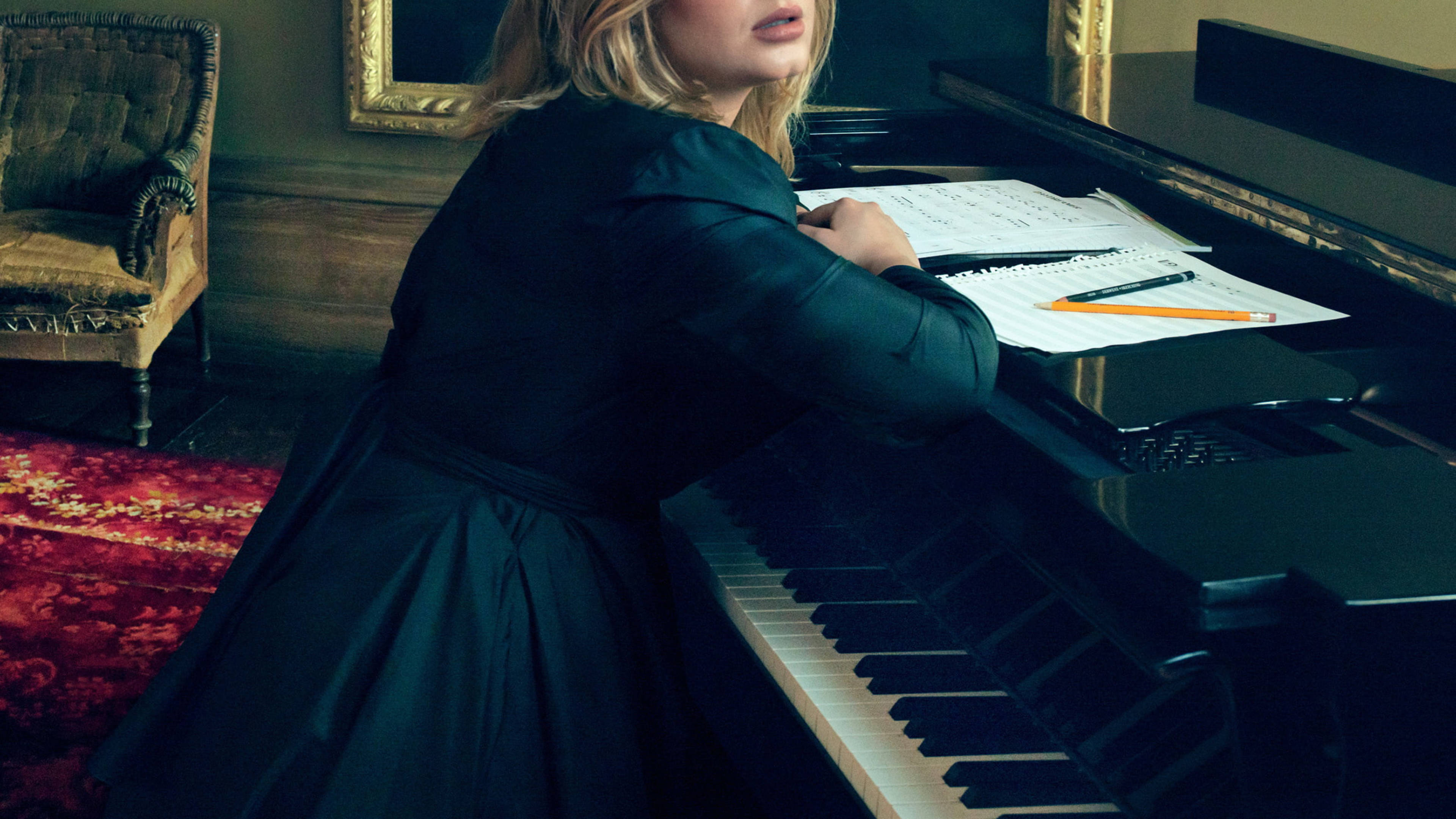 Adele 桌布 壁紙 — 一位身穿深色連衣裙的女性倚靠在一間裝飾華麗的房間裡的三角鋼琴上，房間內有紅色圖案地毯和華麗的椅子。