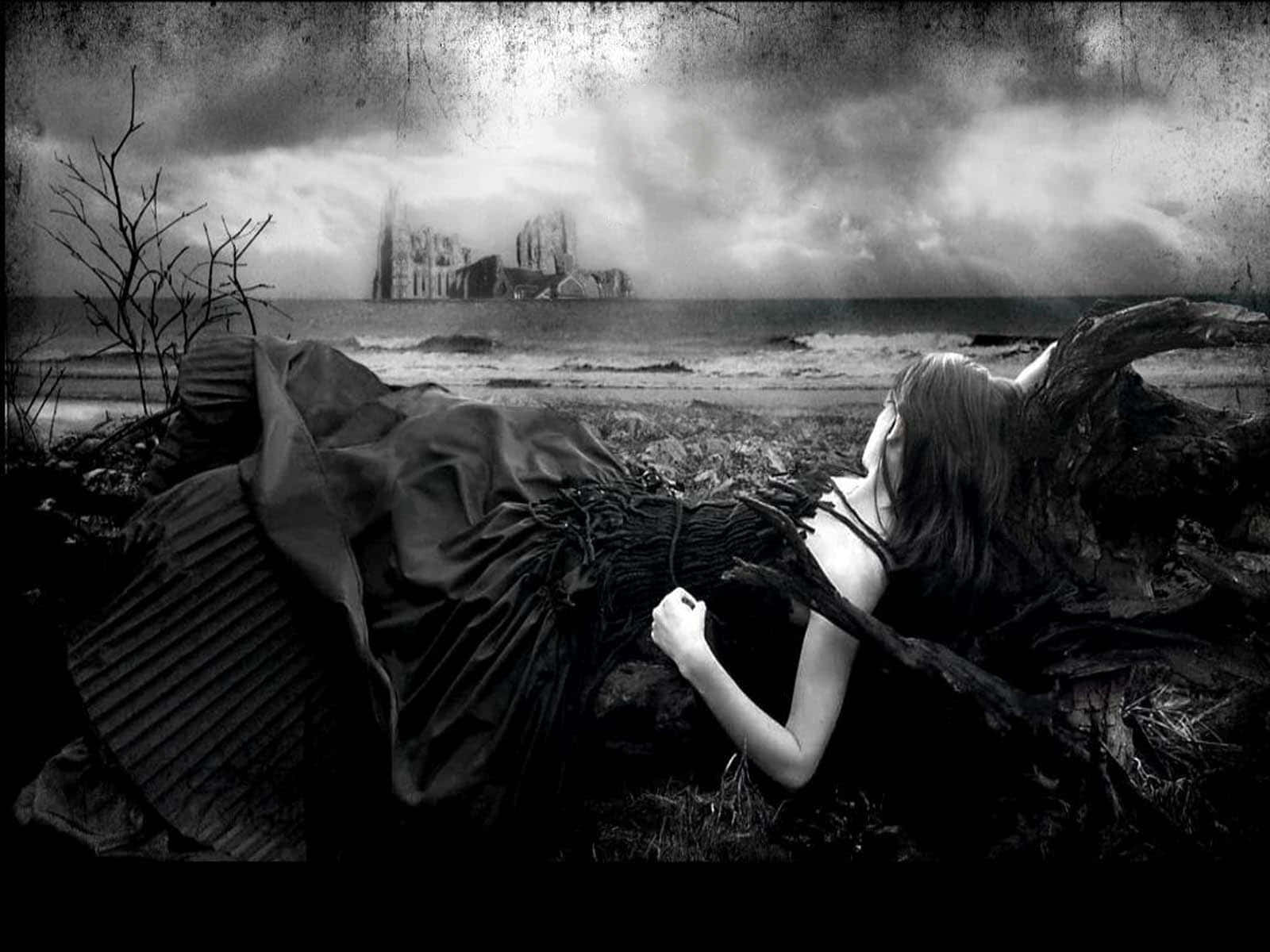 Goth 桌布 壁紙 — 一位身穿深色連衣裙的女性躺在風暴肆虐的海灘上，凝視著陰沉天空下遠處一座廢棄的大教堂。