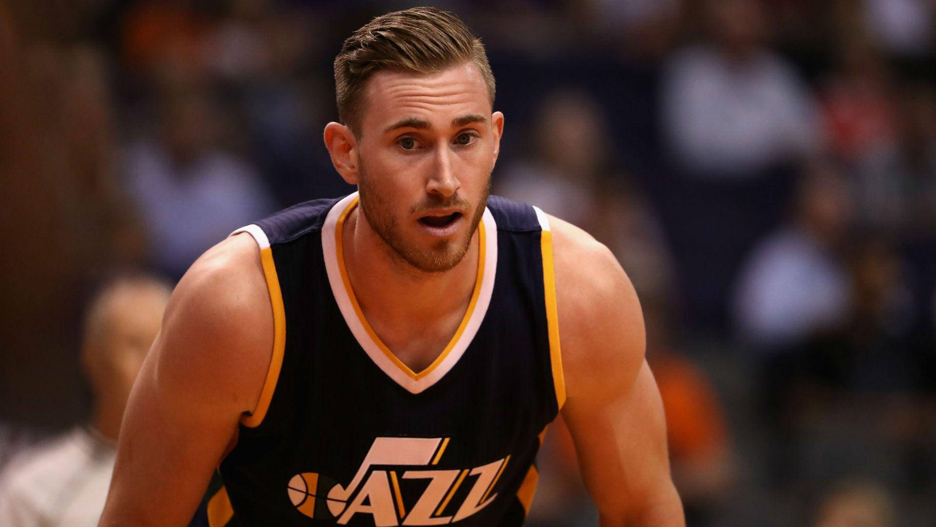 gordon hayward 桌布 壁紙 — 一位身穿深藍色爵士隊球衣的專注籃球運動員，在明亮的場館燈光下於激烈的比賽中向前傾身。