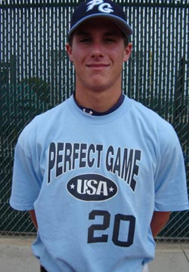 運動 桌布 壁紙 — 一位身穿淺藍色「Perfect Game USA」球衣的年輕棒球運動員，在鐵絲網圍欄背景下自信地微笑。