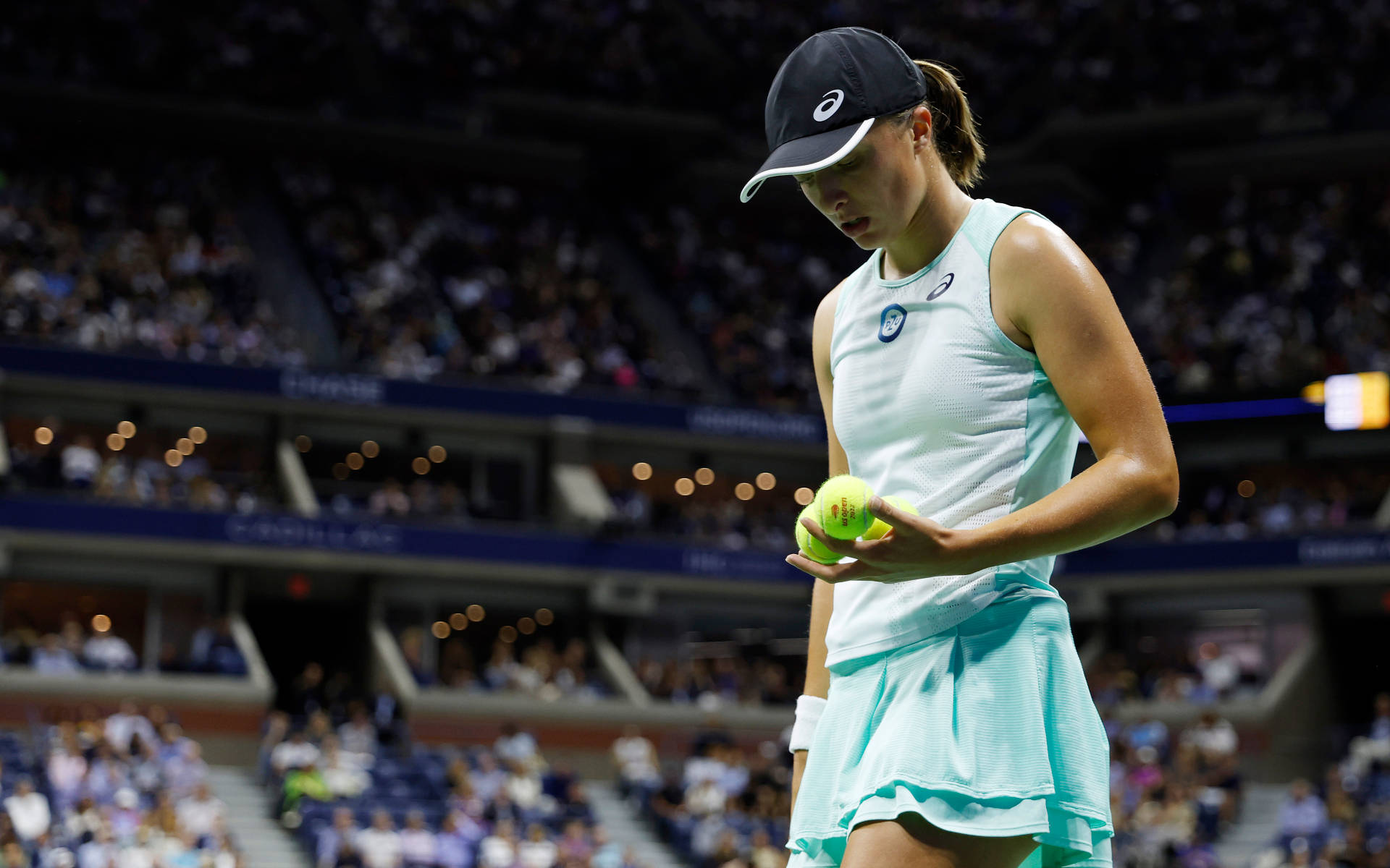 Tennis 桌布 壁紙 — 一位身穿淺藍色服裝的女網球運動員在明亮的體育館球場上低頭看著網球。