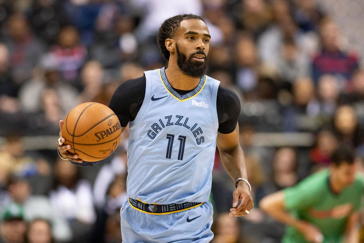 mike conley 桌布 壁紙 — 一位身穿淺藍色灰熊隊球衣的專注籃球運動員，在場館燈光下進行激烈比賽時運著一個Spalding籃球。