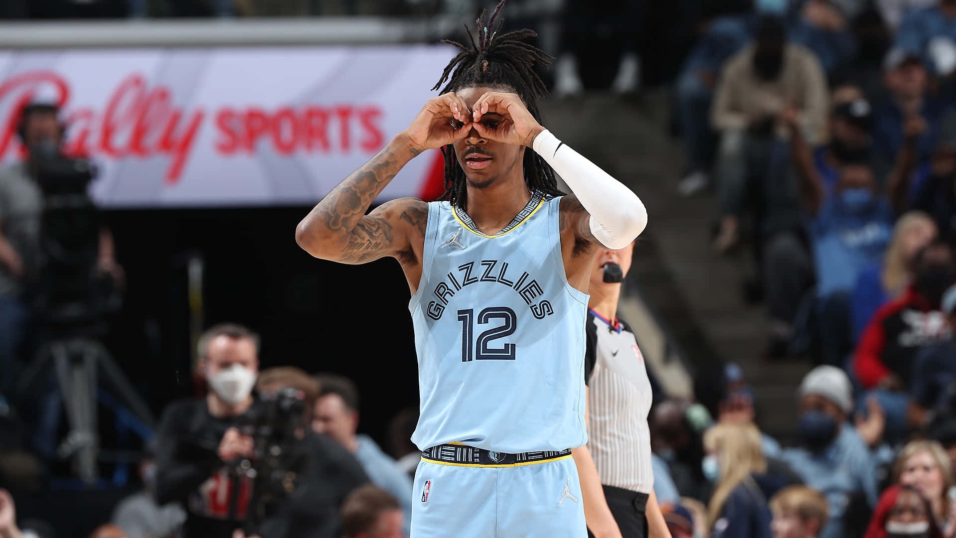 Ja Morant 動圖 桌布 壁紙 — 一位身穿淺藍色灰熊隊球衣的籃球運動員在比賽中用雙手遮住眼睛，背景是模糊的觀眾。