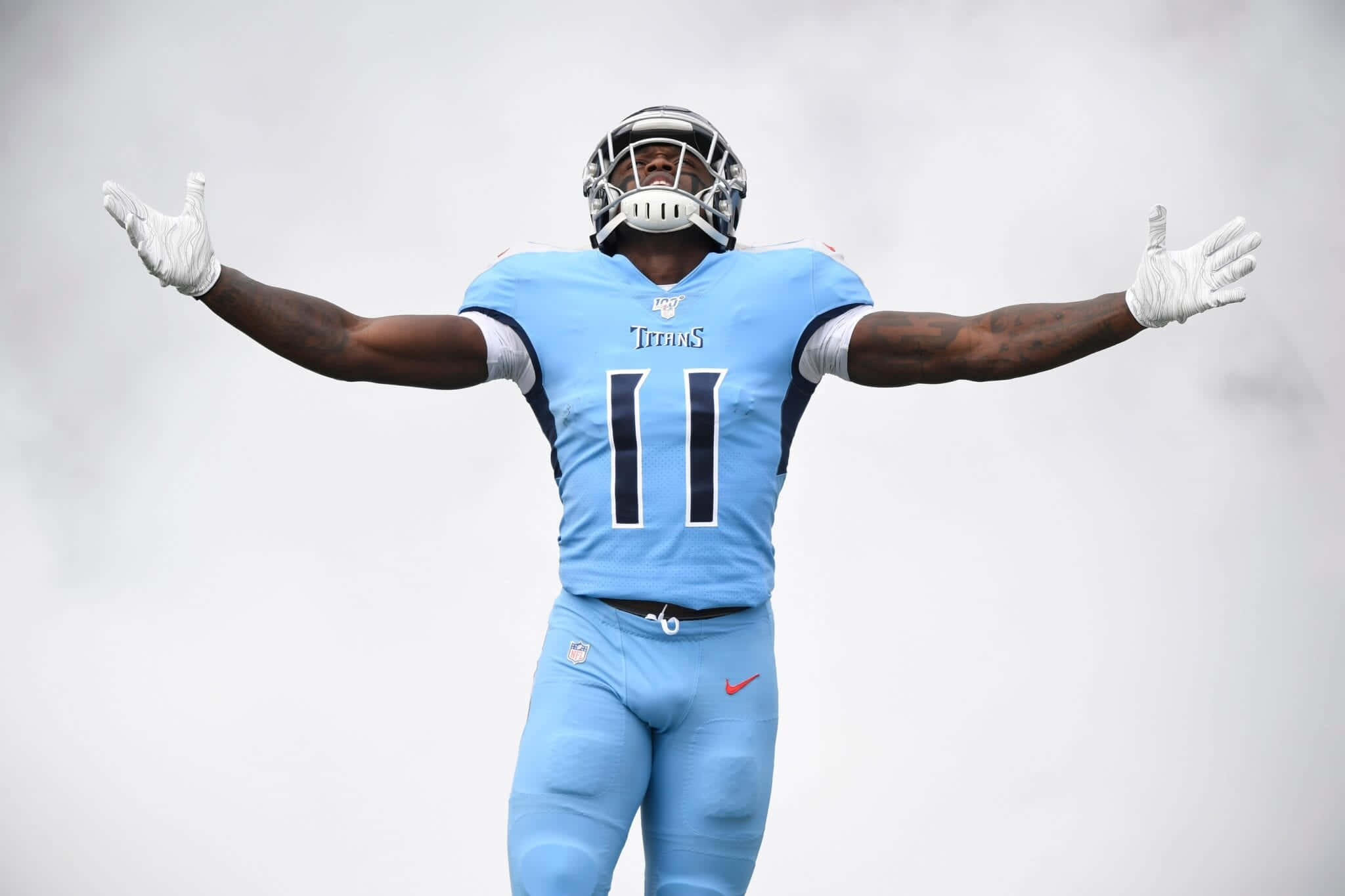 Tennessee Titans 桌布 壁紙 — 一位身穿淺藍色球衣的田納西泰坦隊美式足球員，在陰雲密佈的天空下張開雙臂。