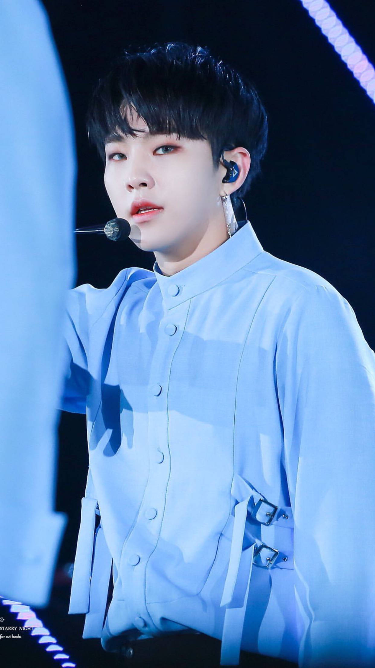 Hoshi 桌布 壁紙 — 一位身穿淺藍色舞台服的年輕男表演者在明亮的藍色舞台燈光下對著麥克風唱歌。