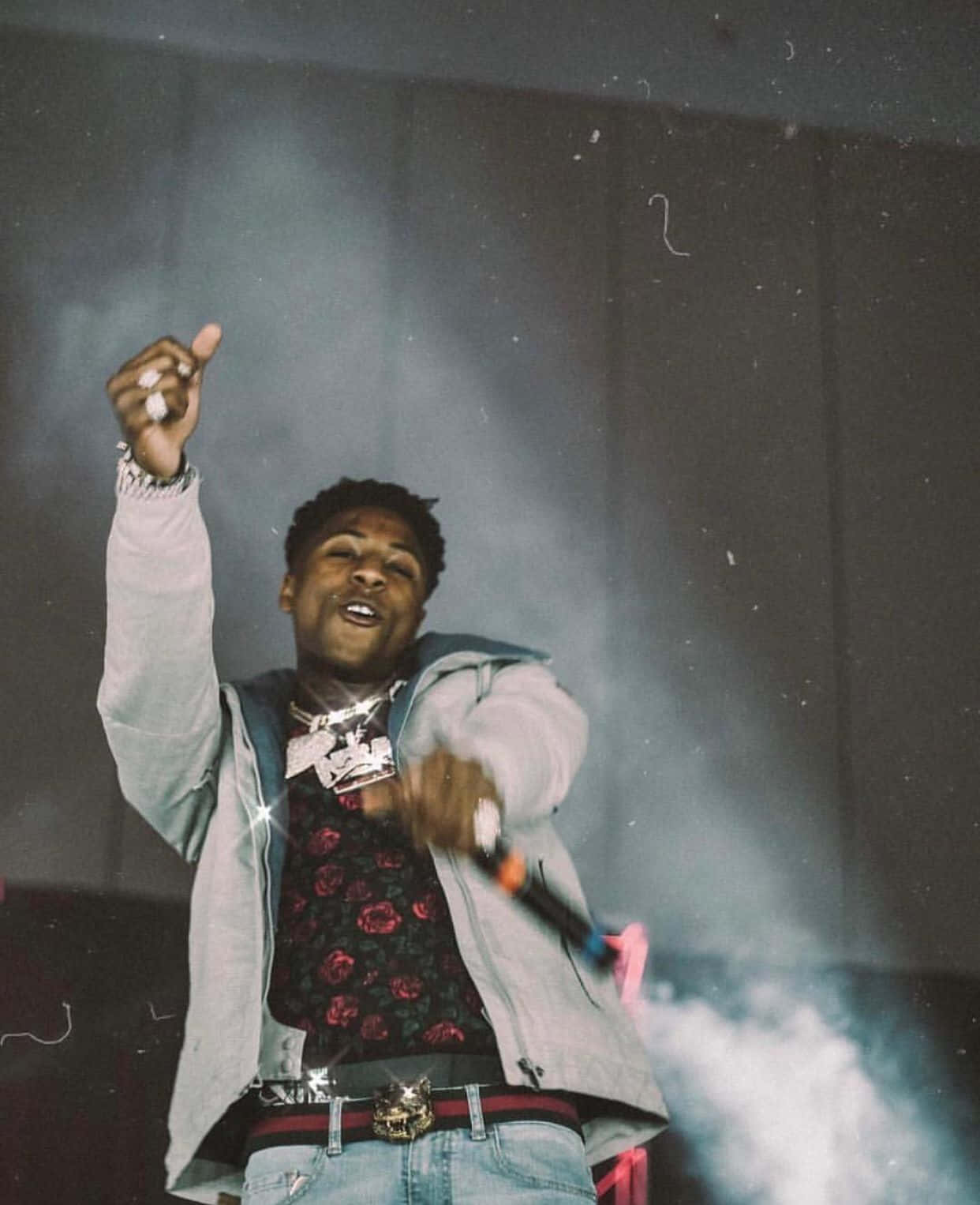 Youngboy 桌布 壁紙 — 一位身穿灰色外套和花卉襯衫的年輕男子在煙霧繚繞的舞台上充滿活力地表演。