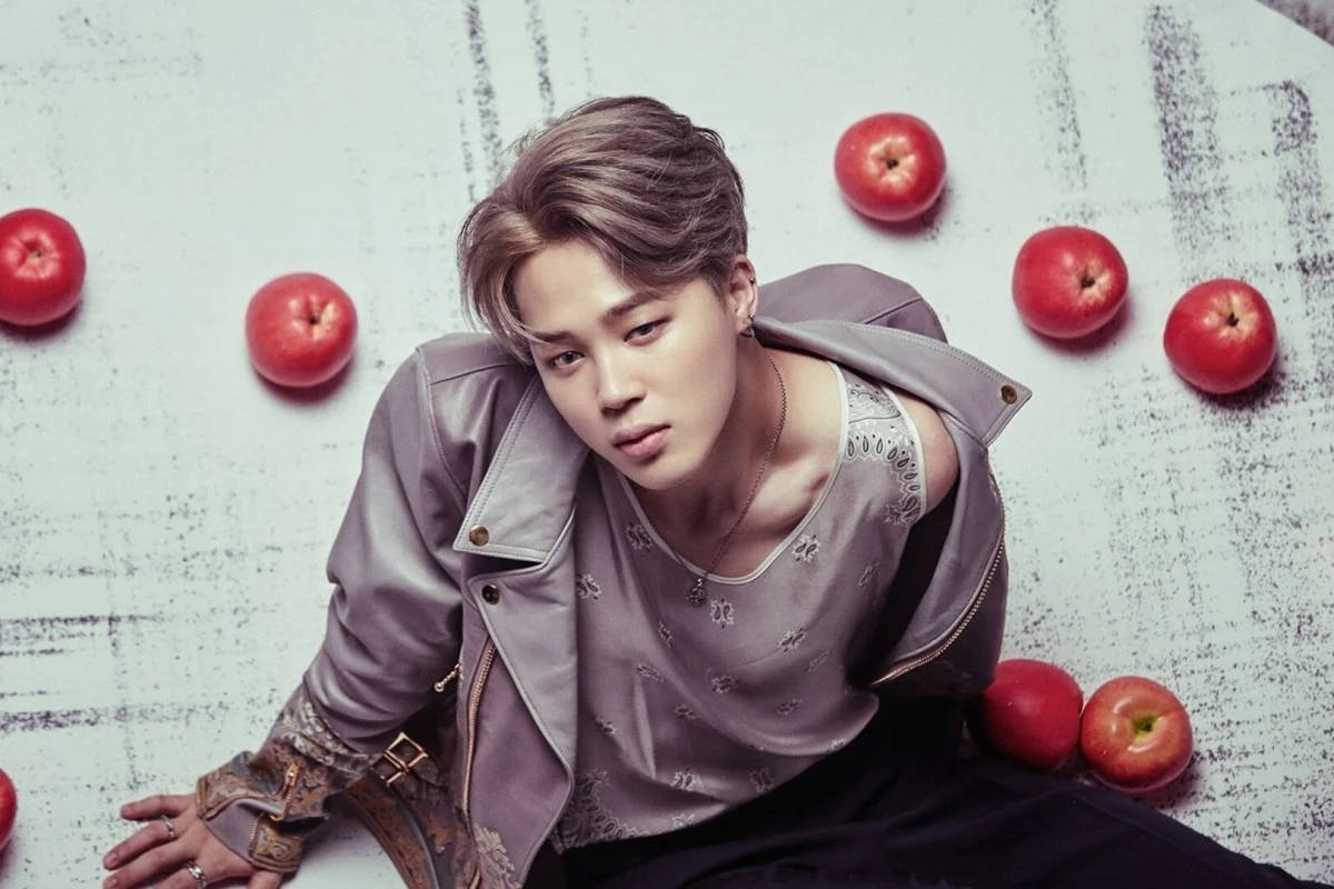 BTS 智旻 桌布 壁紙 — 一位身穿灰色外套的年輕男子坐在質感白色表面上，周圍環繞著紅蘋果。