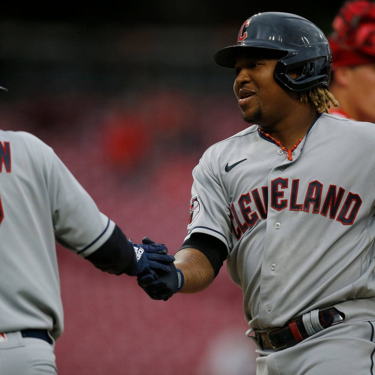 Jose Ramirez 桌布 壁紙 — 一位身穿灰色球衣的克里夫蘭棒球運動員在紅色球場上與隊友握手。