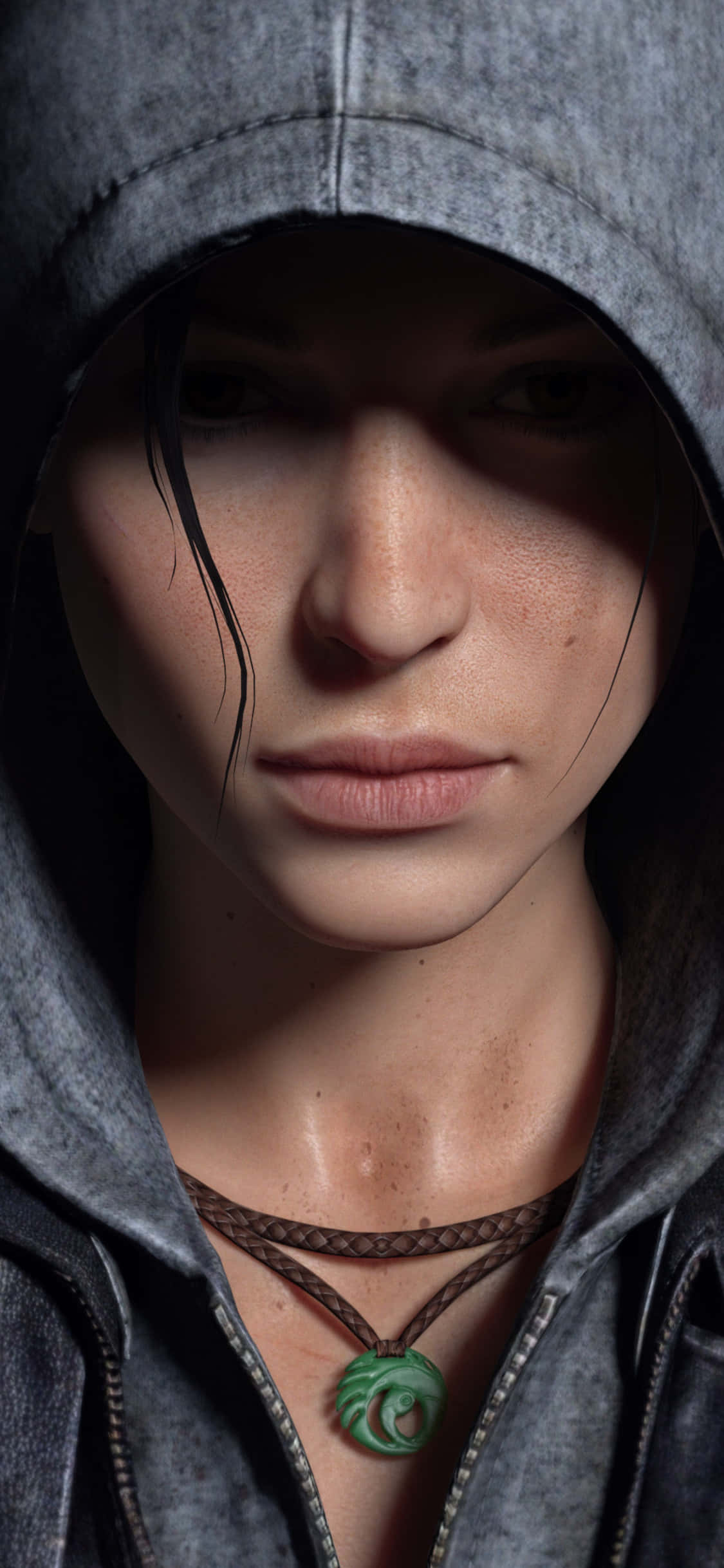 Pixel 3 Shadow Of The Tomb Raider 桌布 壁紙 — 一位身穿灰色連帽外套、戴著綠色螺旋吊墜項鍊的女性在戲劇性燈光下的特寫。