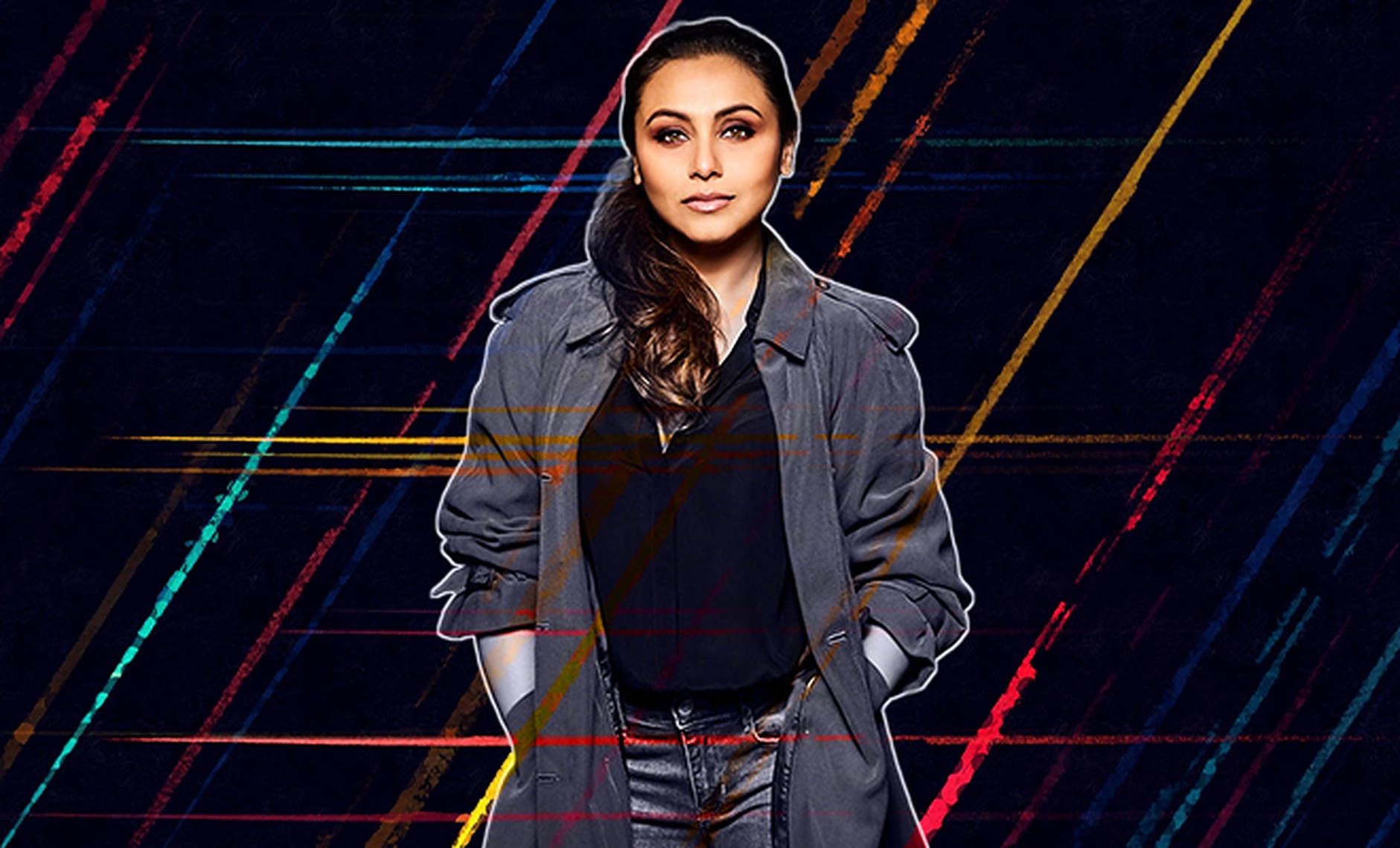Rani Mukerji 桌布 壁紙 — 一位身穿灰色風衣的女性自信地站在帶有鮮豔霓虹線條的深色背景前。