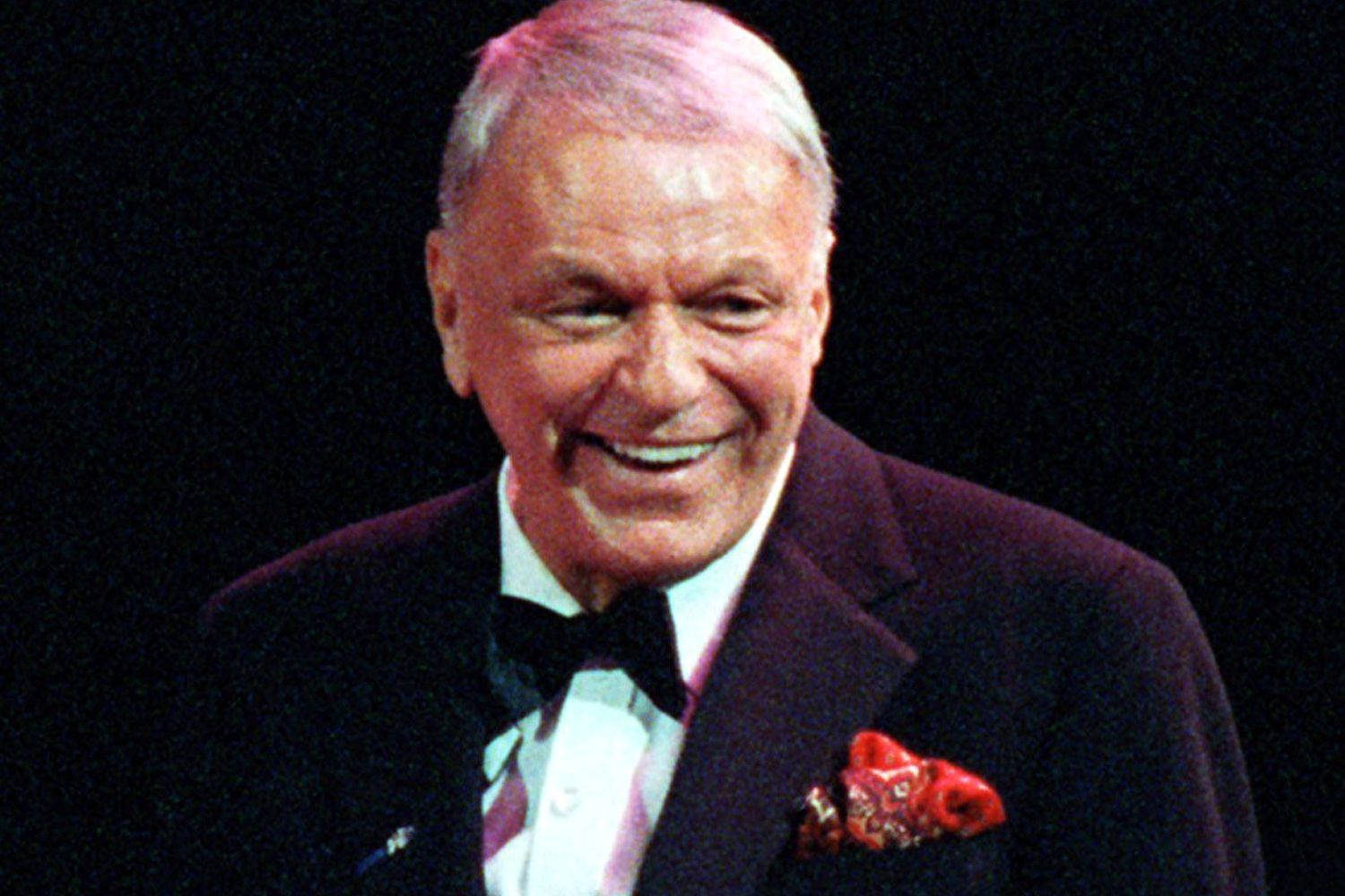 Sinatra 桌布 壁紙 — 一位身穿燕尾服、口袋巾為紅色的快樂年長男士，在深色背景中綻放光彩。