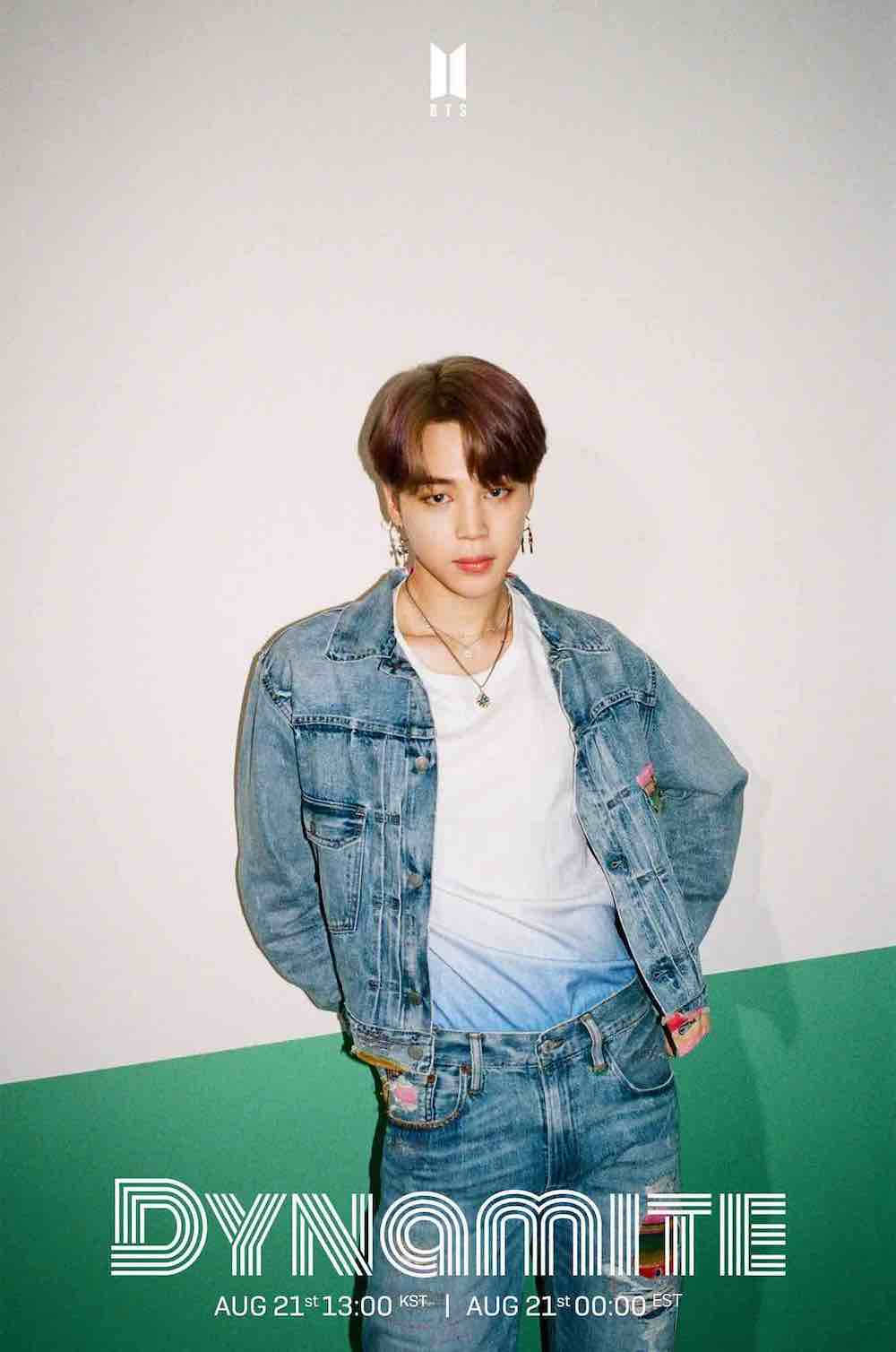 Bts Jimin 桌布 壁紙 — 一位身穿牛仔外套和牛仔褲的年輕男子自信地站在一面白色和綠色分割的牆前，下方有「DYNAMITE」文字。