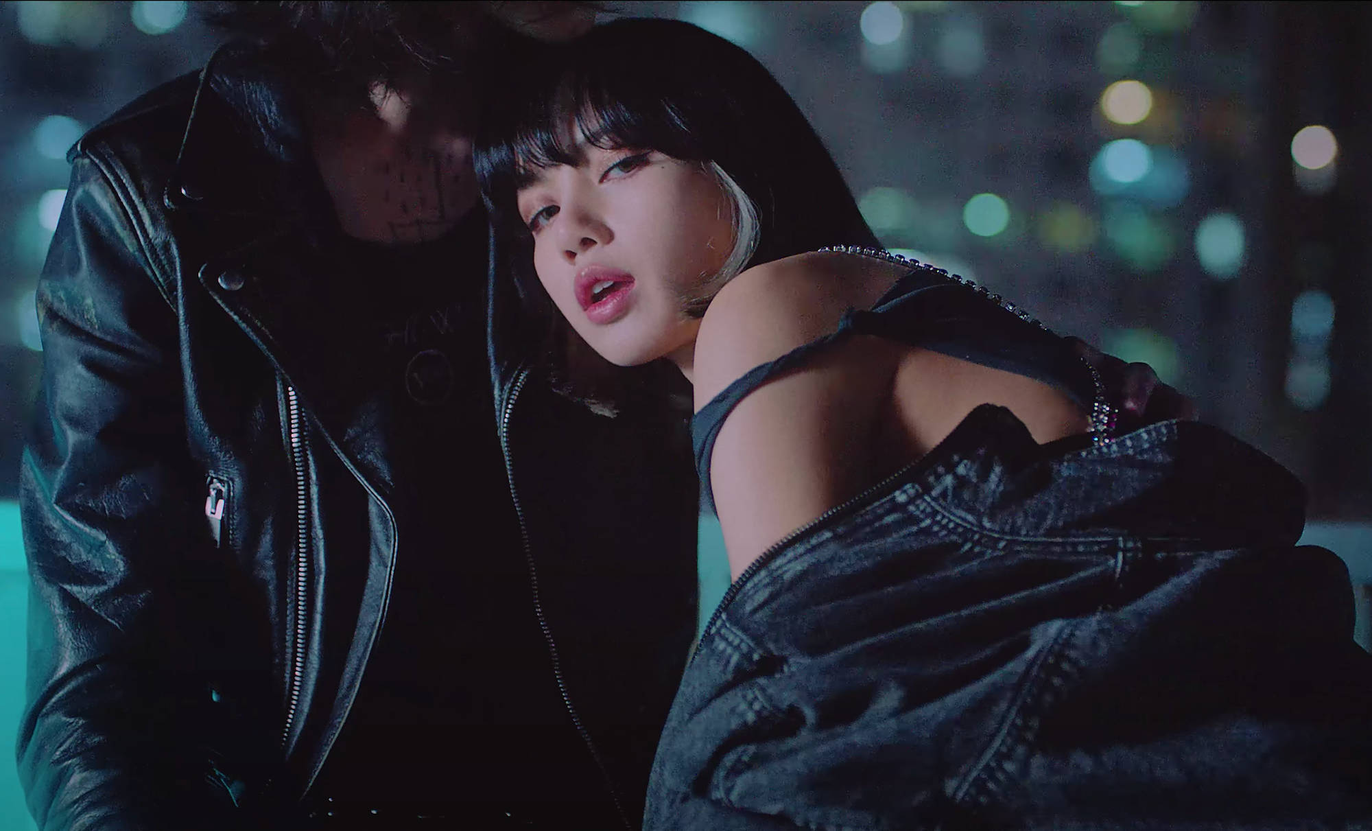 Lalisa 桌布 壁紙 — 一位身穿牛仔外套和黑色上衣的女性在夜晚的霓虹城市燈光下靠著一位身穿皮夾克的男性。