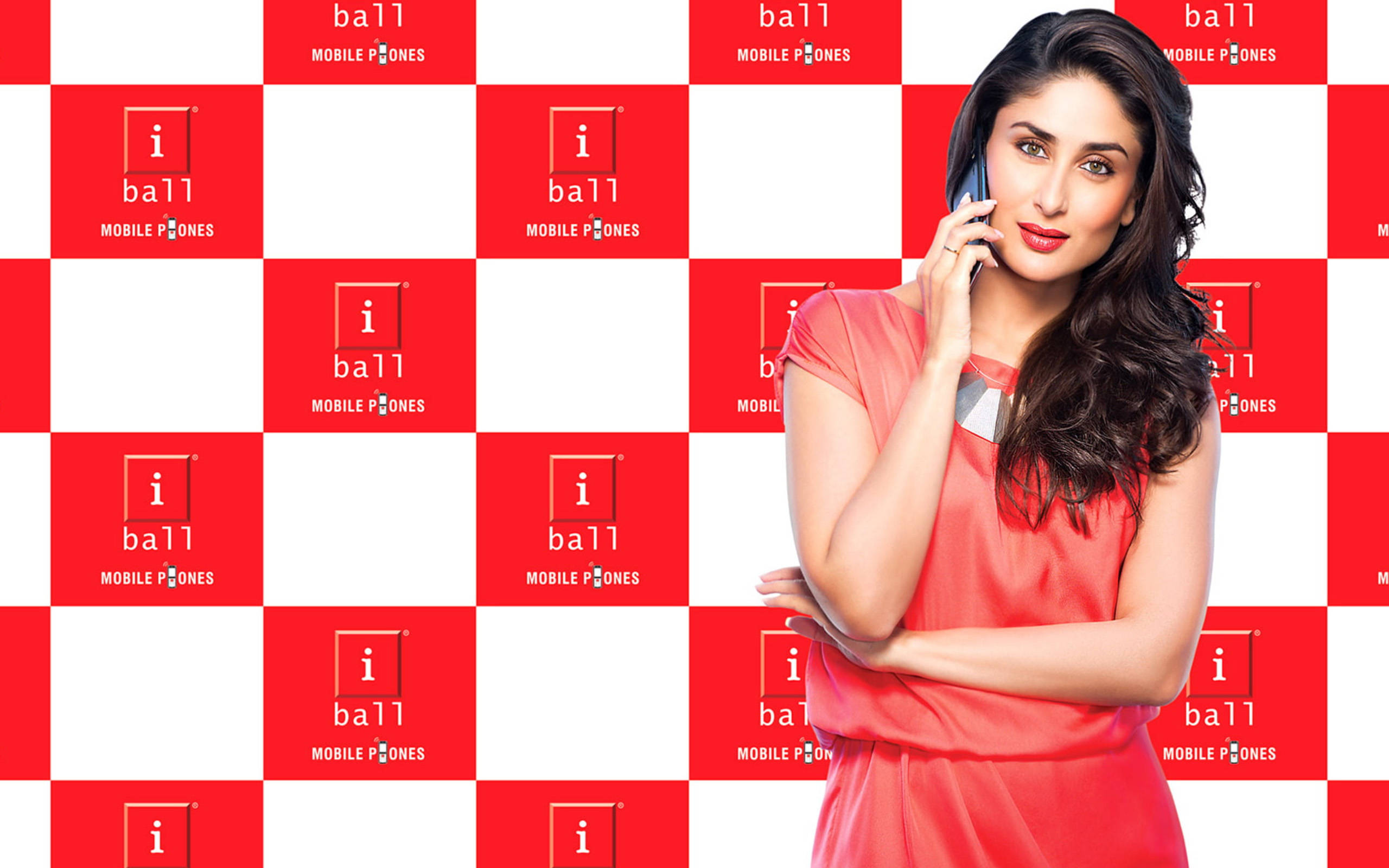 Kareena 桌布 壁紙 — 一位身穿珊瑚色連衣裙的女性將手機貼在耳邊，背景是紅白格子的 i ball mobile phones。