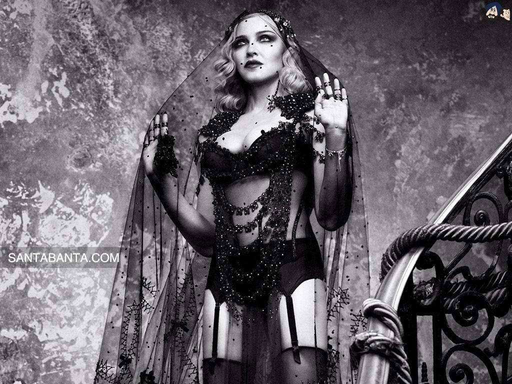 Madonna 桌布 壁紙 — 一位身穿珠飾黑色內衣和頭紗的女性在華麗樓梯旁的紋理牆壁前戲劇性地擺姿勢。
