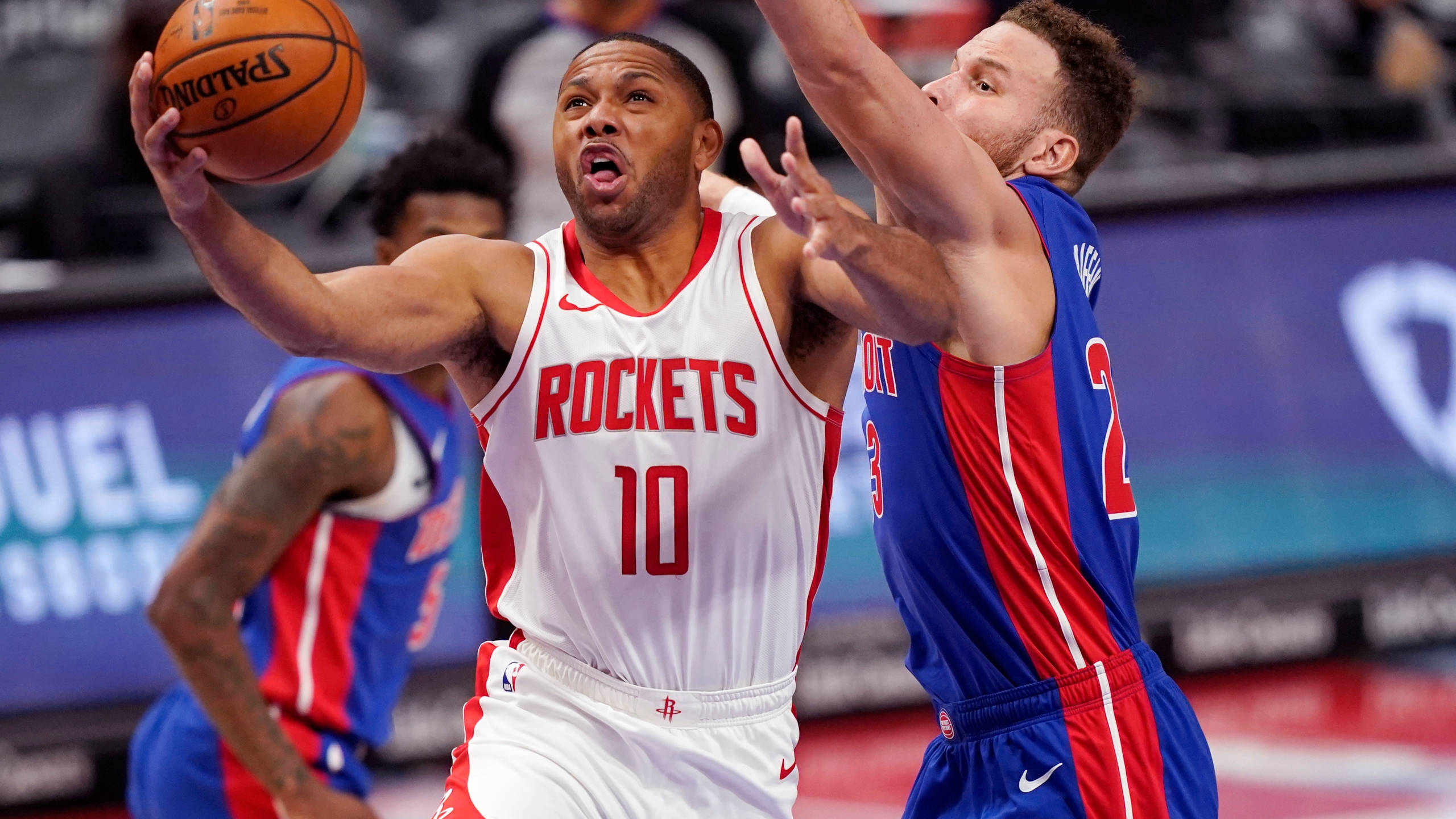 eric gordon 桌布 壁紙 — 一位身穿白色10號球衣的休士頓火箭球員在激烈的籃球比賽中，越過身穿藍紅色的底特律活塞防守球員。