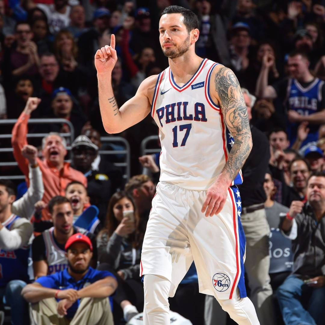 Jj Redick 桌布 壁紙 — 一位身穿白色17號球衣的費城76人籃球運動員在激烈的比賽中豎起一根手指向上示意，背景是歡呼的球迷。