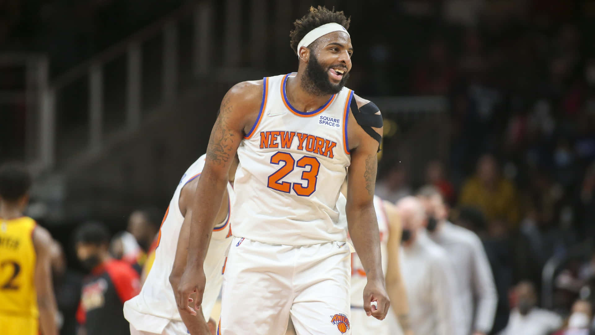 NBA 桌布 壁紙 — 一位身穿白色23號球衣的紐約尼克籃球運動員在比賽中微笑，背景是模糊的人群。