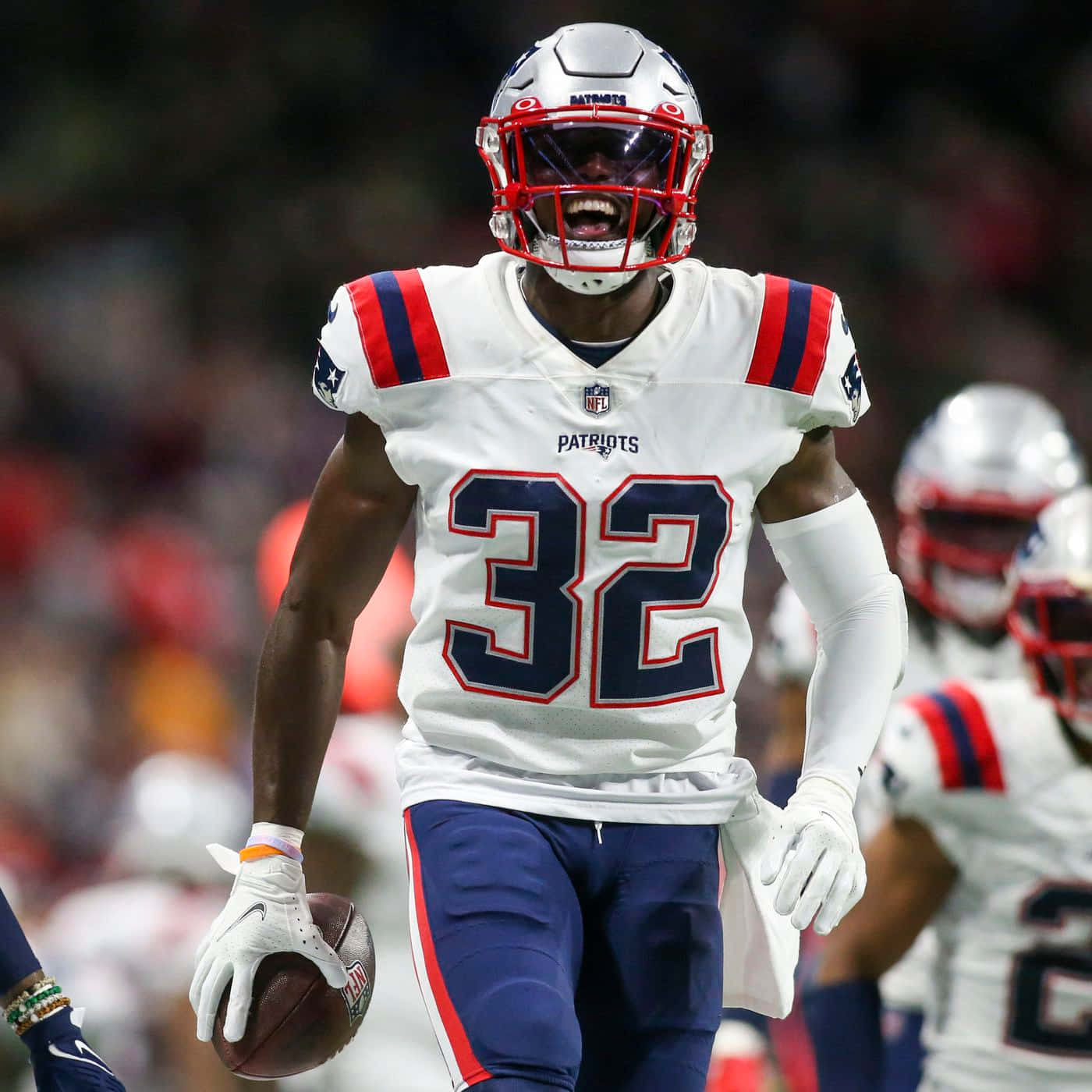 Devin Mccourty 桌布 壁紙 — 一位身穿白色32號球衣的新英格蘭愛國者隊美式足球員在夜間比賽中，於球場燈光下帶球奔跑。