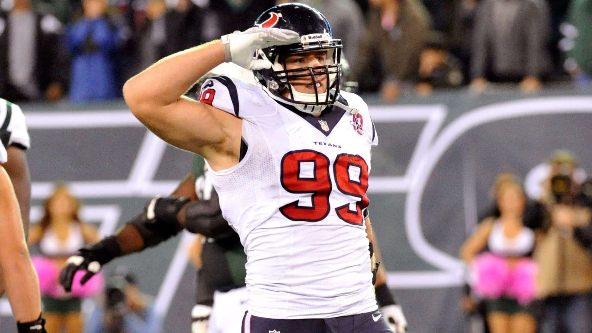 Jj Watt 桌布 壁紙 — 一位身穿白色99號球衣的休士頓德州人美式足球員在球場燈光下向球迷致敬。
