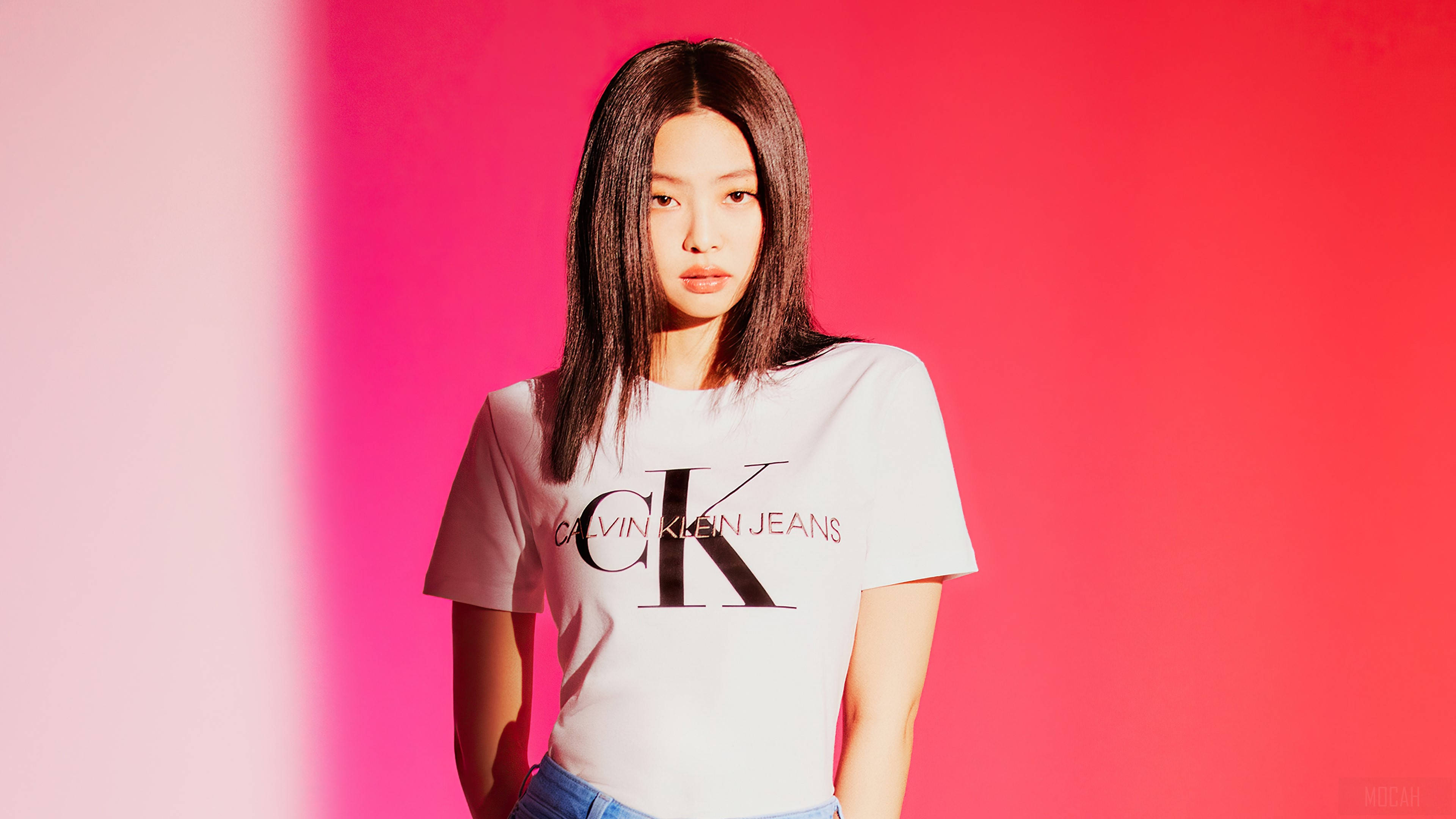 Klein 桌布 壁紙 — 一位身穿白色Calvin Klein Jeans T恤的女性站在充滿活力的粉紅和白色漸變背景前。