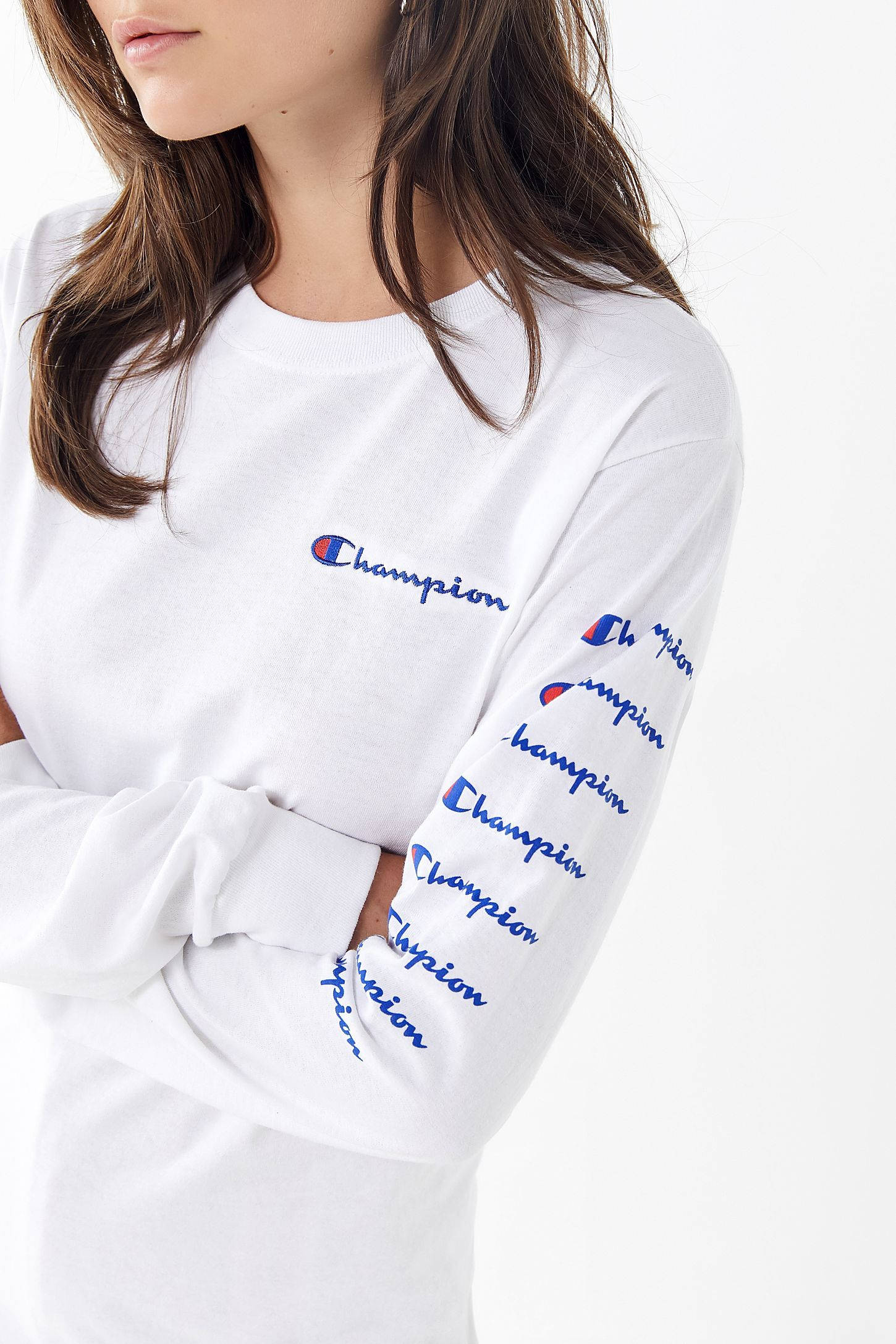 Champion 桌布 壁紙 — 一位身穿白色Champion衛衣、胸前和袖子上有藍色標誌刺繡的女性，站在純白色背景前。