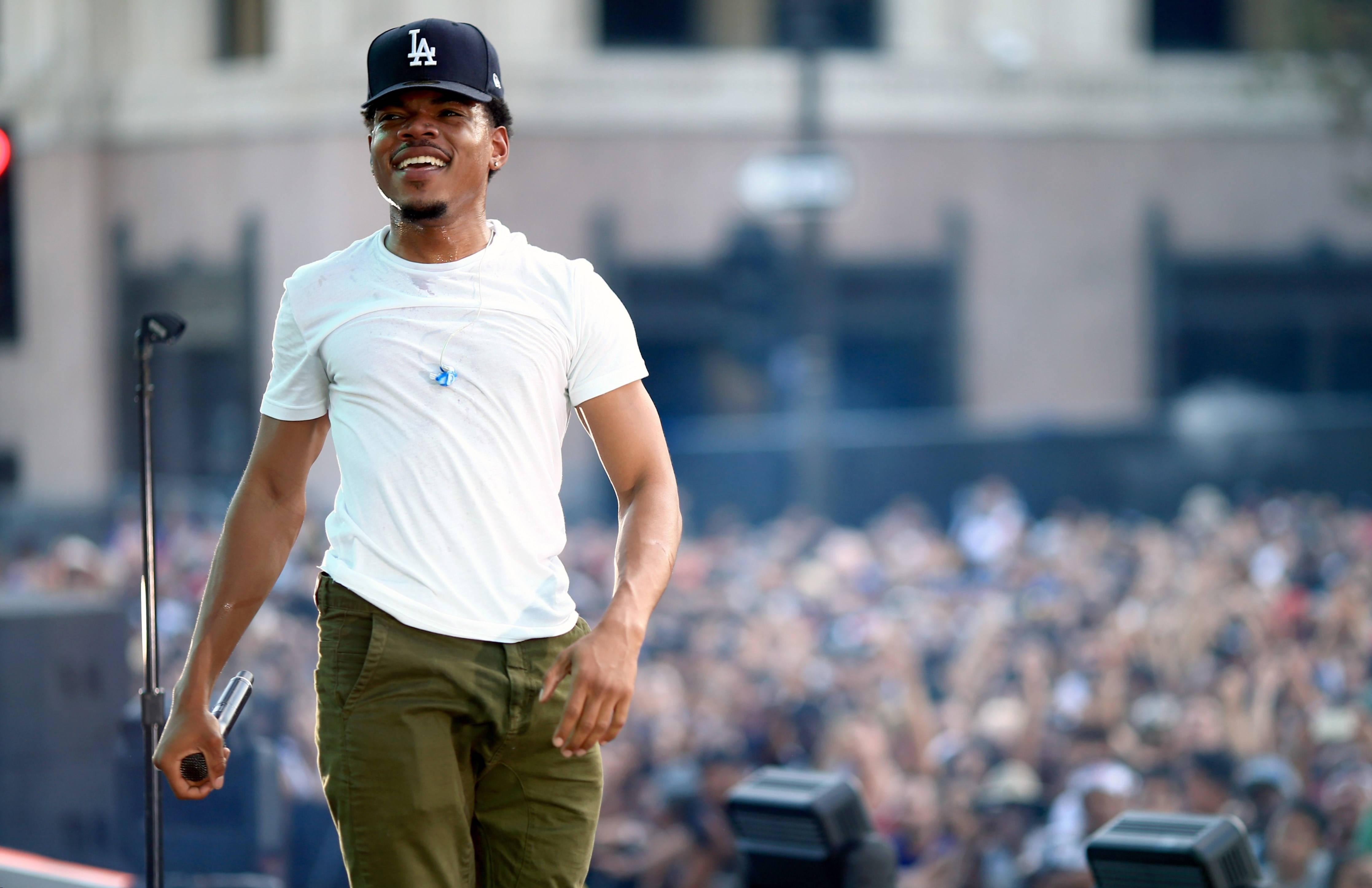 chance 桌布 壁紙 — 一位身穿白色T恤和帽子的微笑表演者自信地走在舞台上，面對歡呼的人群。