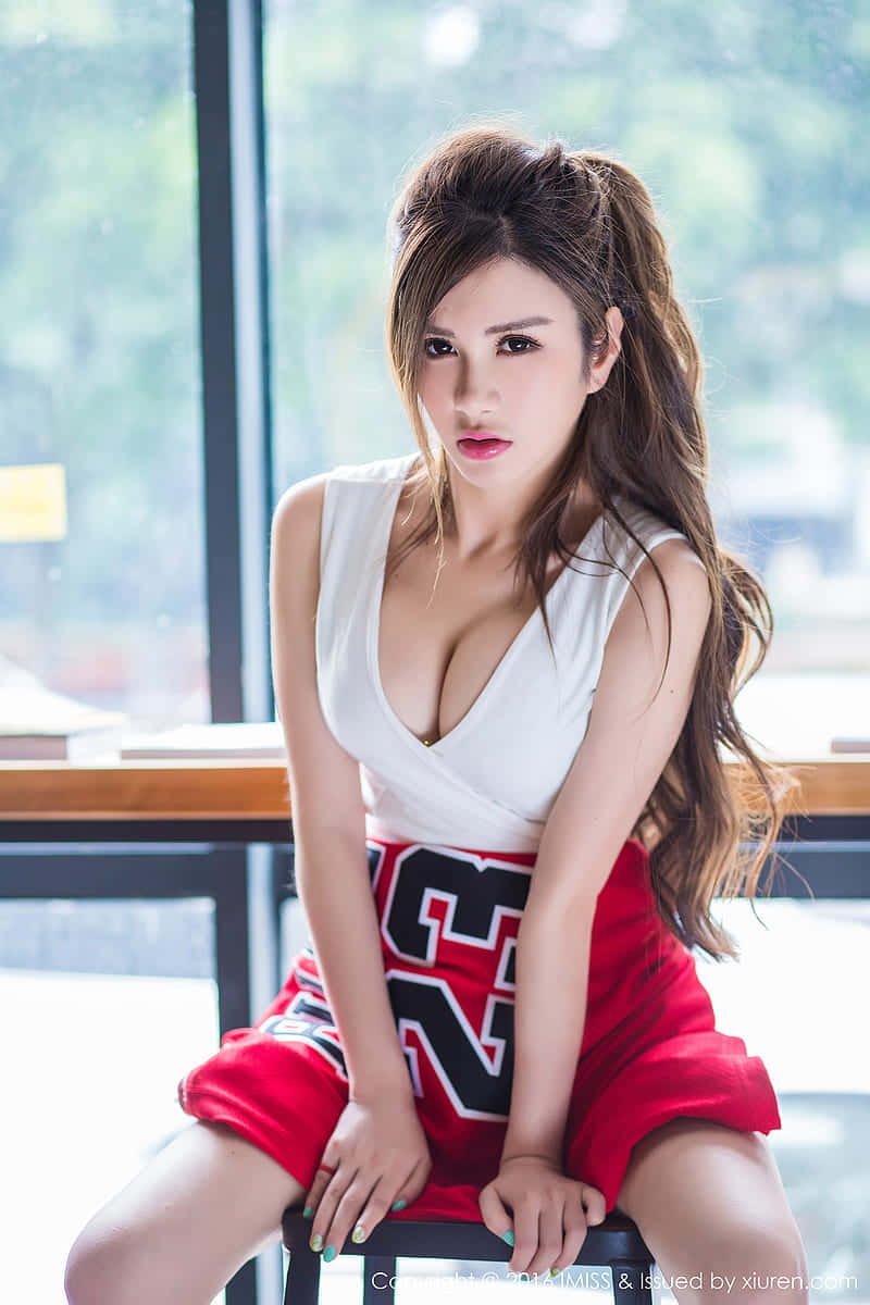 Pretty Woman 桌布 壁紙 — 一位身穿白色上衣和紅色啦啦隊短褲的女性自信地坐在明亮窗邊的凳子上。