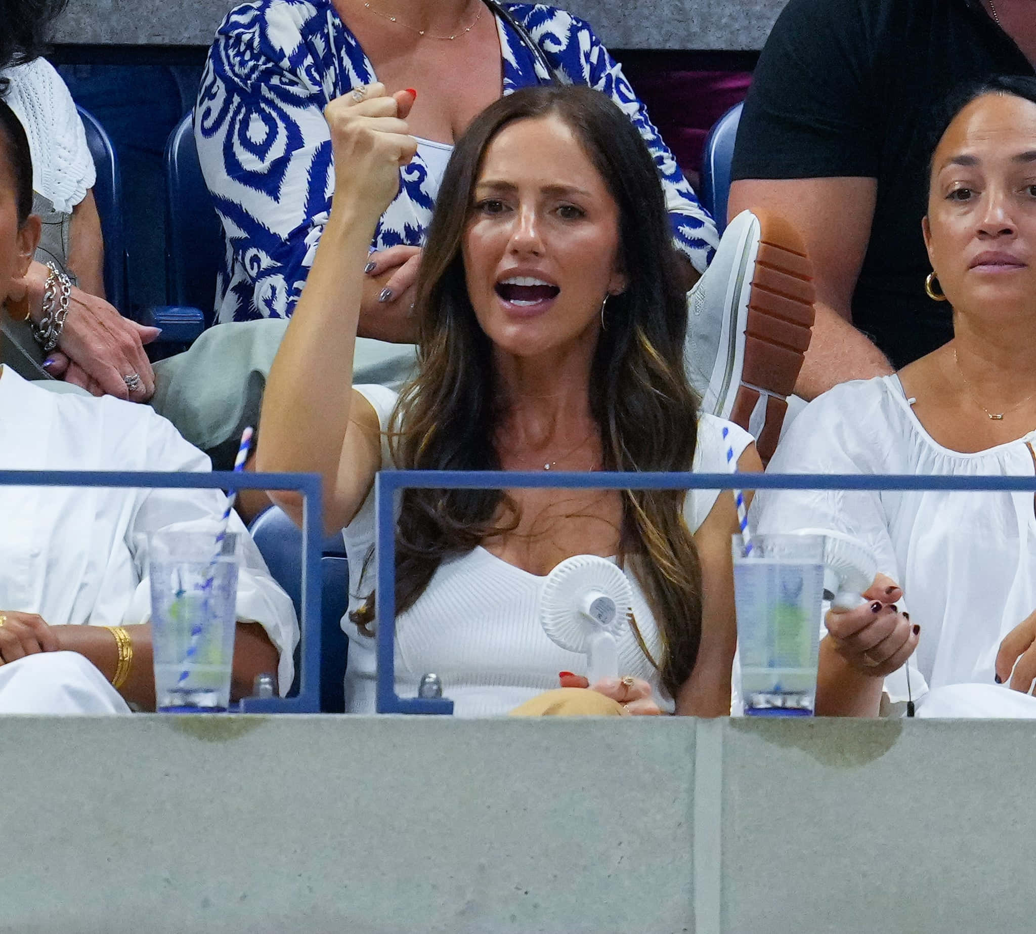minka kelly 桌布 壁紙 — 一位身穿白色上衣的女性在網球比賽中熱情歡呼，手持小扇並舉起拳頭。